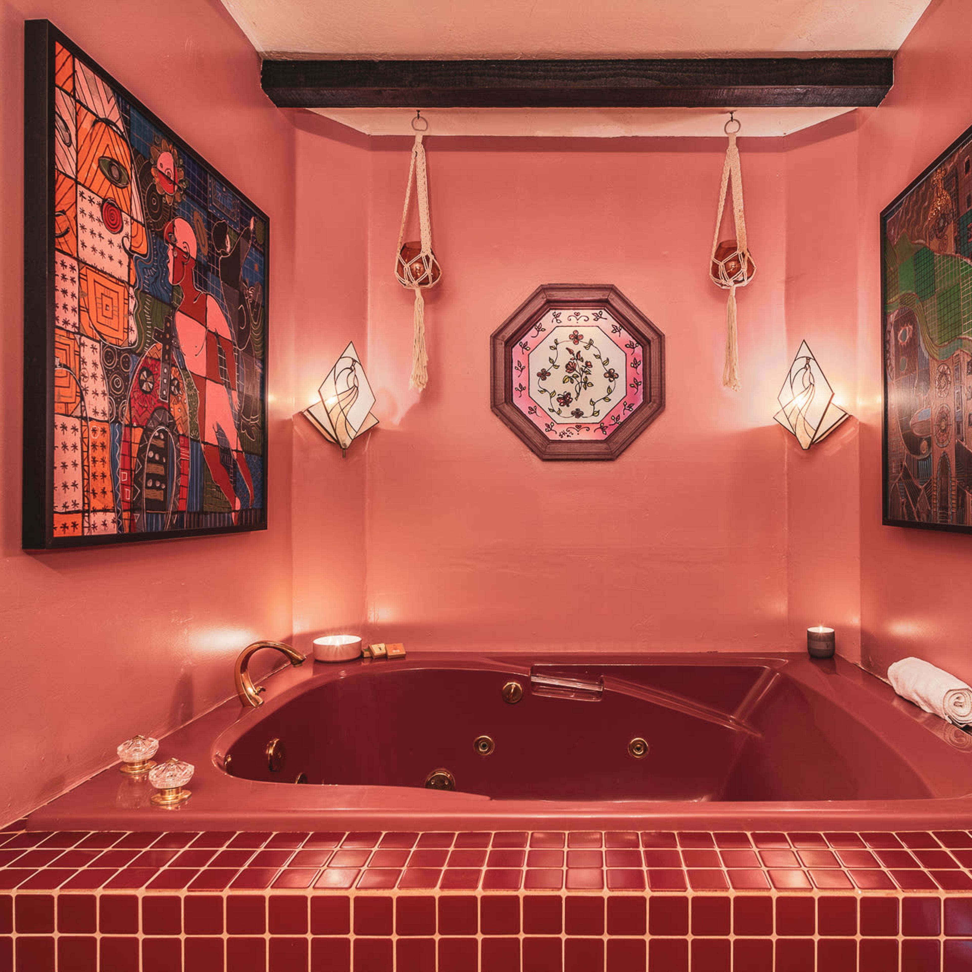 A corner whirlpool bathtub surrounded by pink walls and framed artworks.