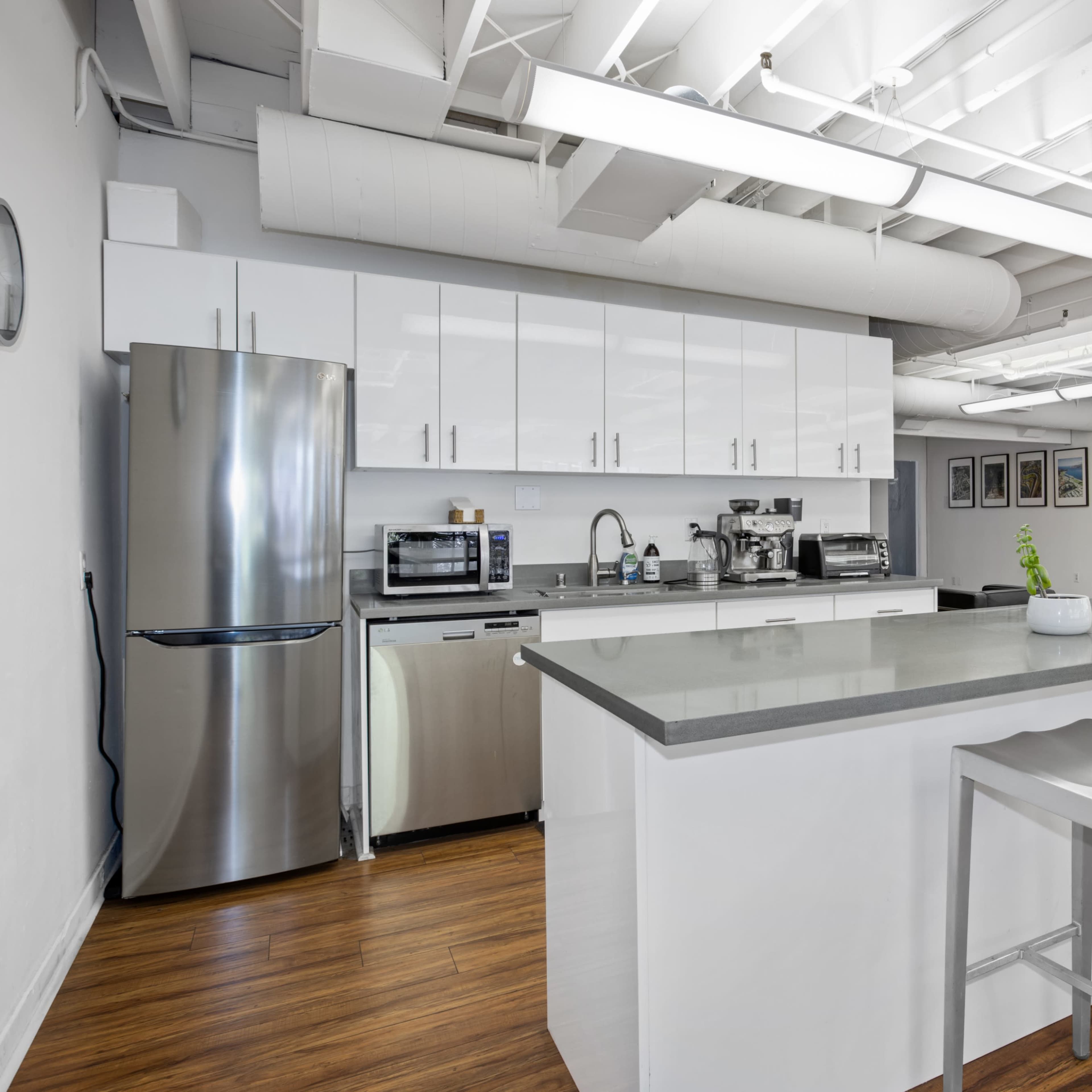 A modern kitchen features stainless steel appliances, white cabinetry, and a gray countertop with bar seating.