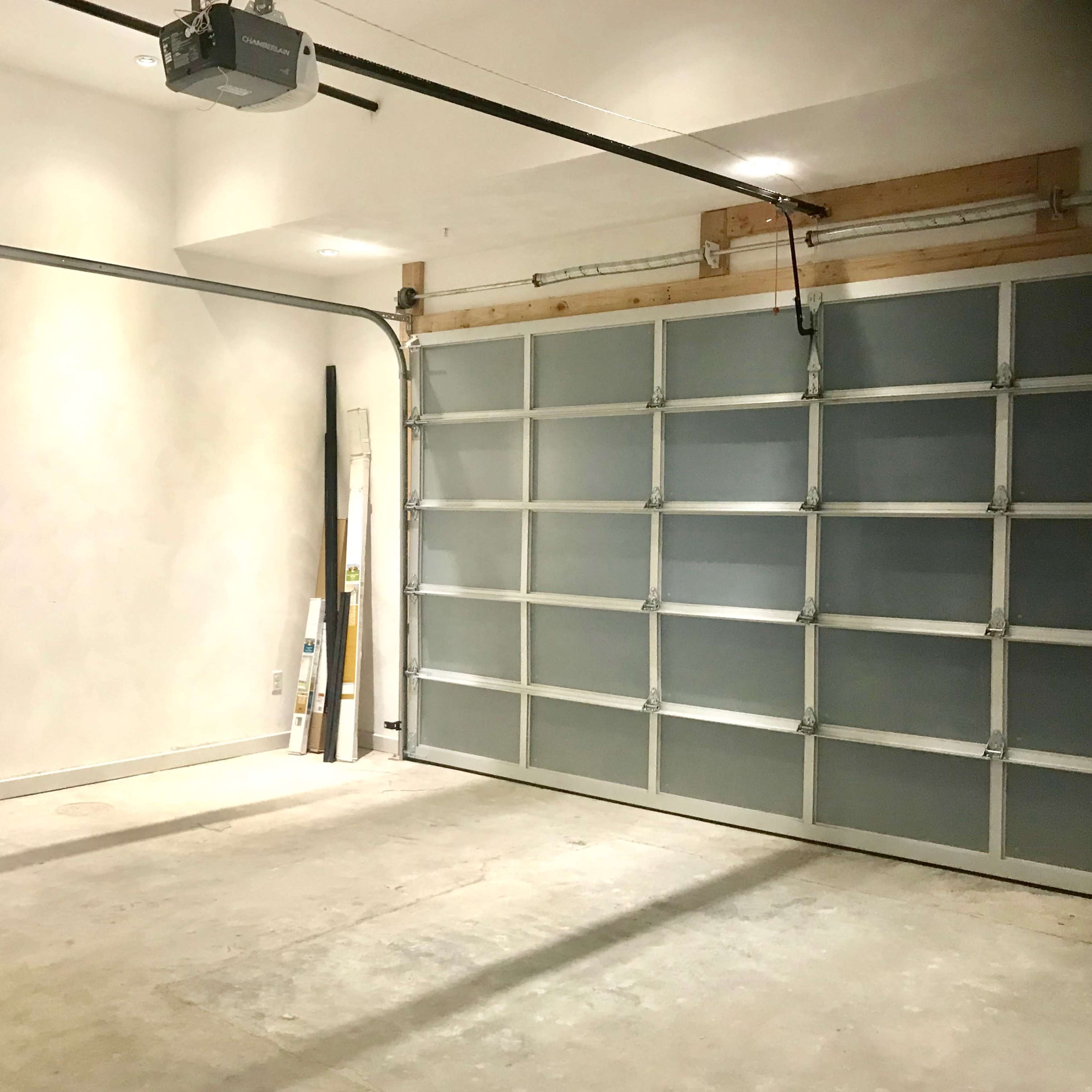 An empty garage with a sectional door and concrete flooring.