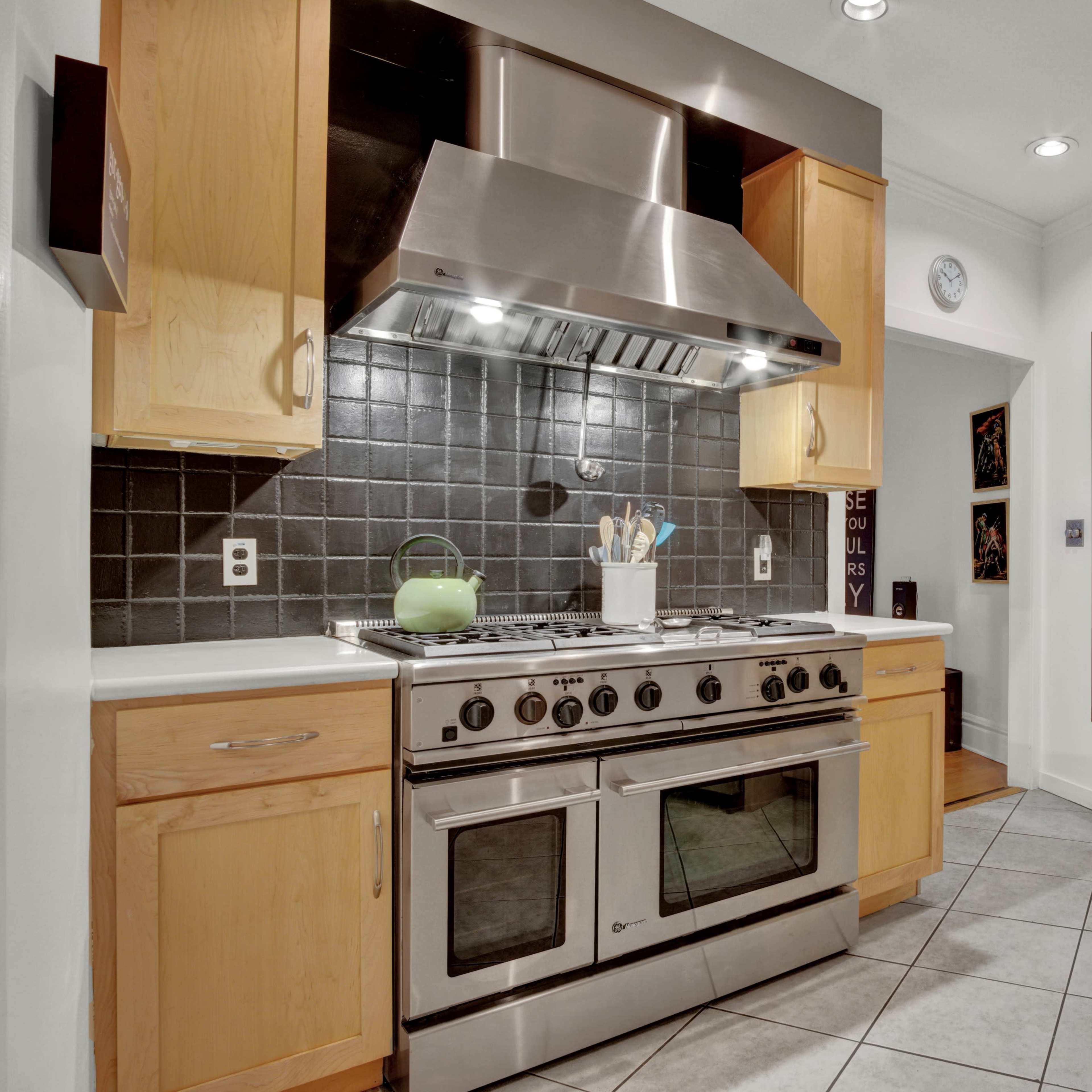A kitchen with wooden cabinets, stainless steel appliances, and a large gas range beneath a hood.