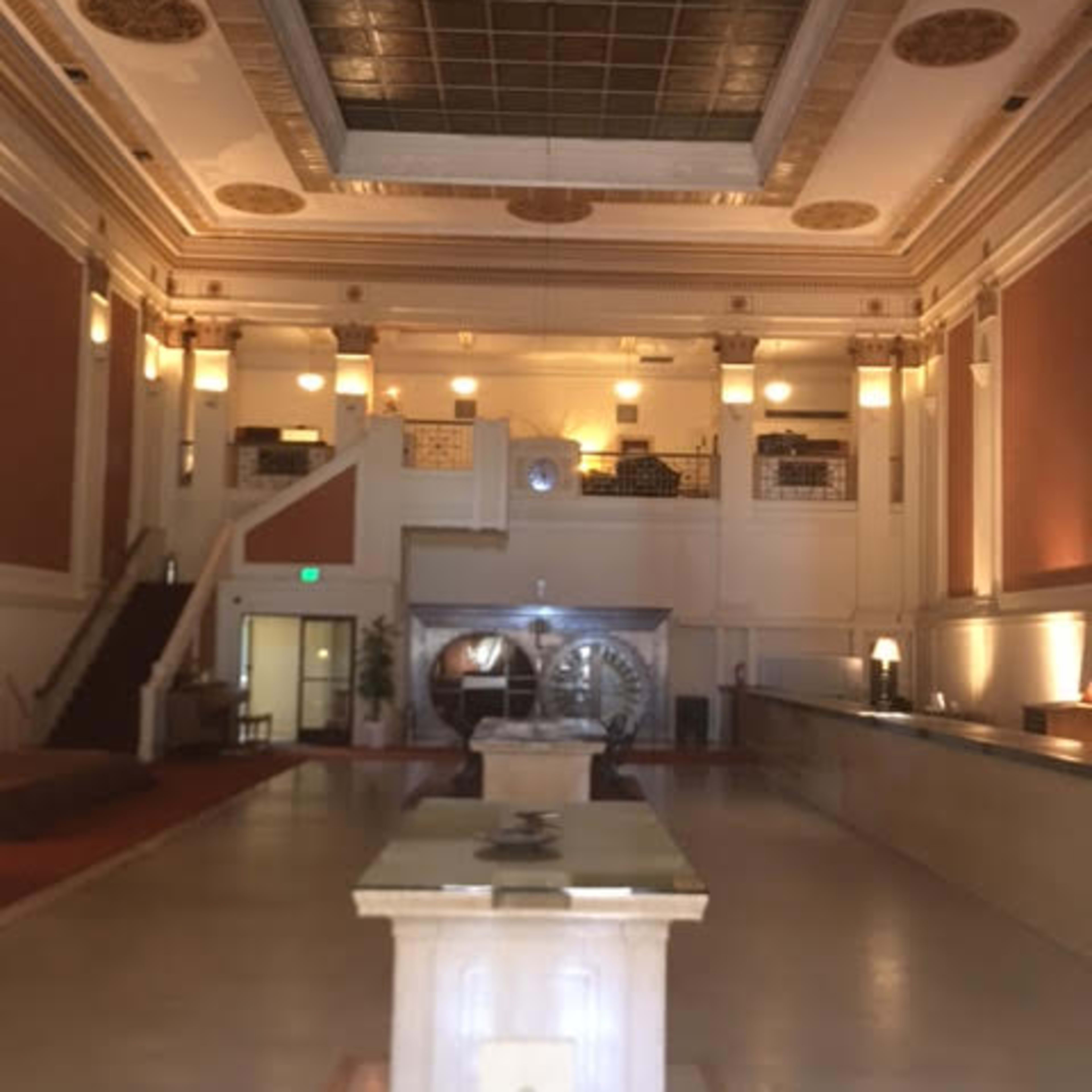 A spacious, art deco styled lobby with a high ceiling, two large circular sculptures, and a reception desk along one side.