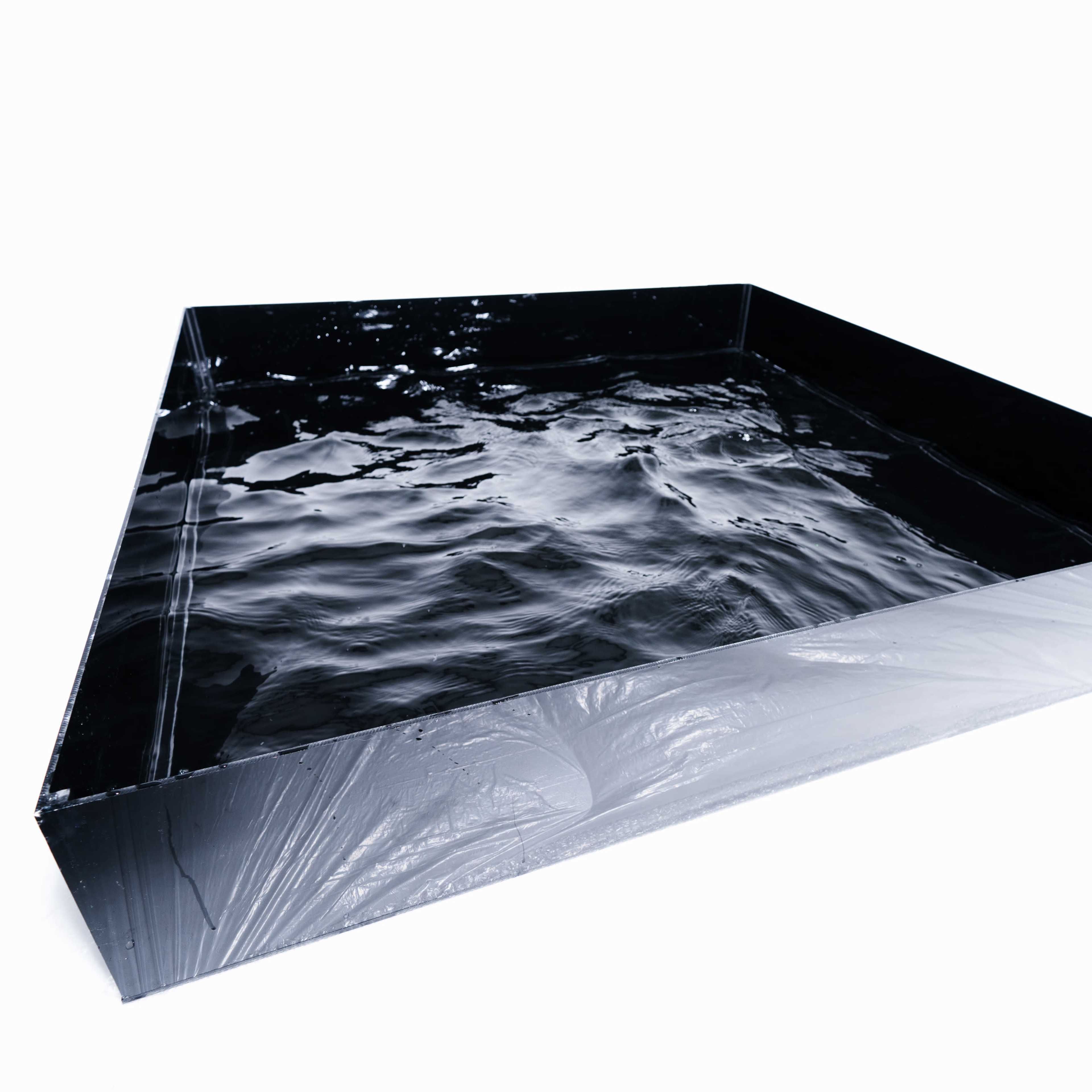 A large, black rectangular basin filled with still water sits on a white surface.