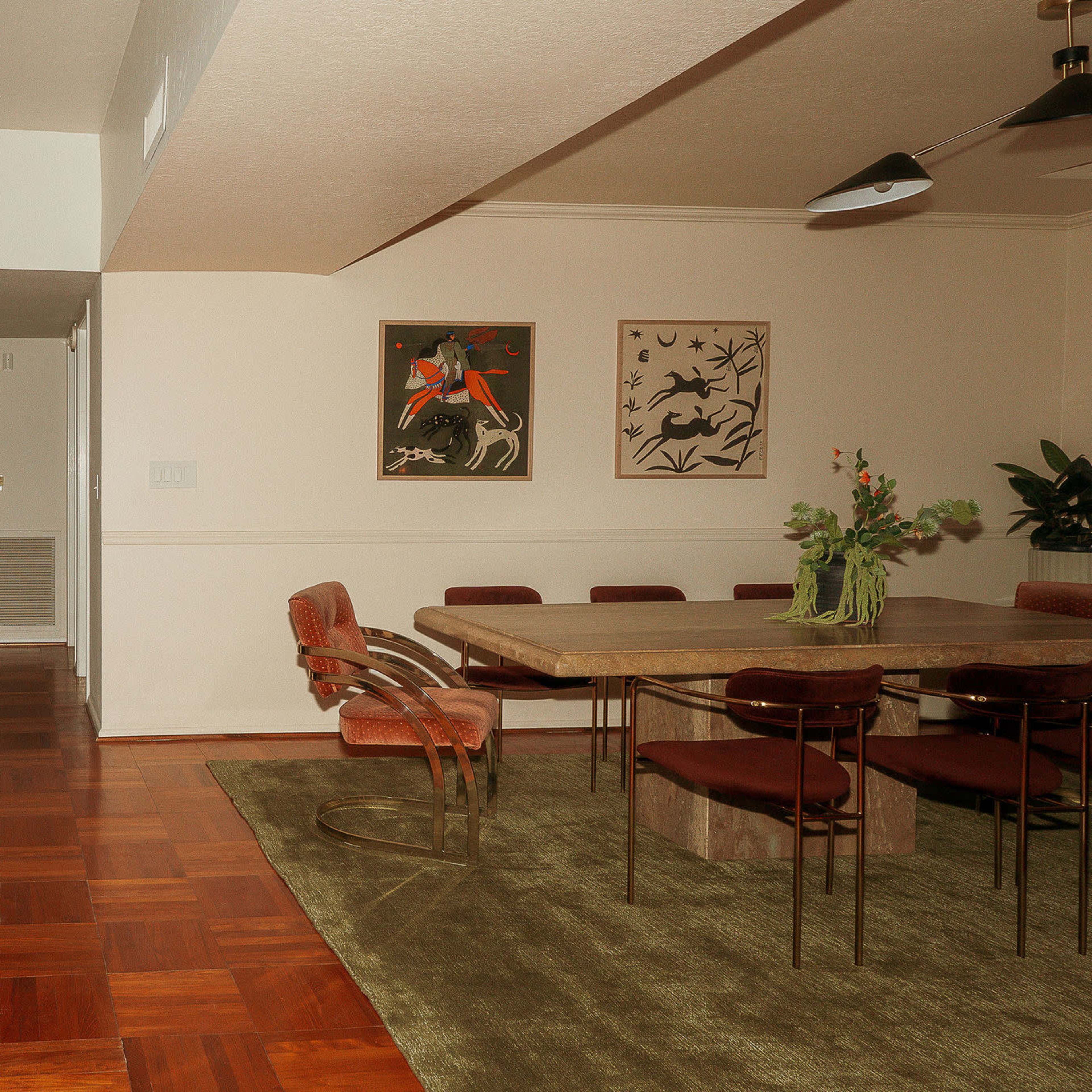 A spacious dining area featuring a large table surrounded by chairs, with a hallway and a door leading to another room in the background.