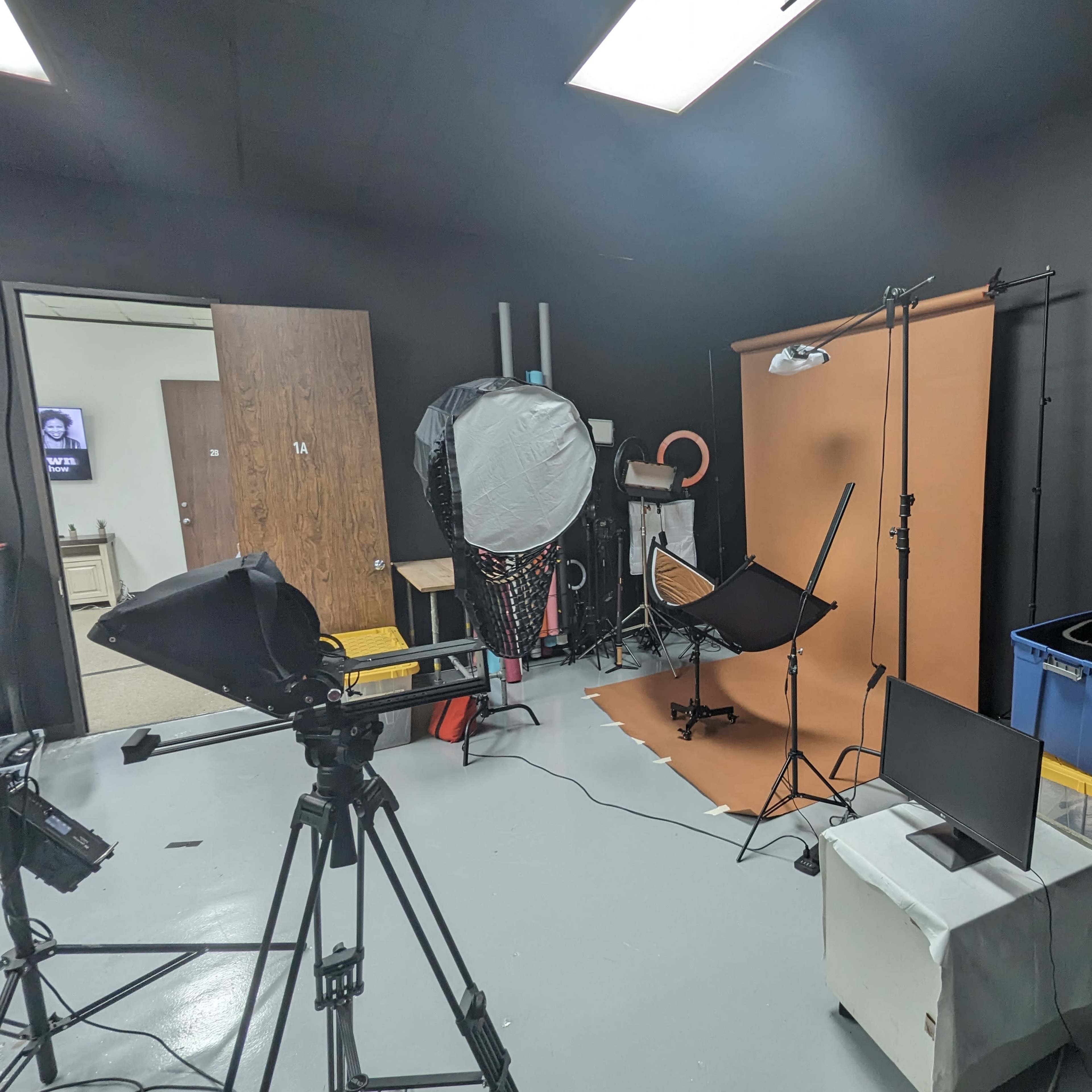 A photography studio setup with a backdrop, lighting equipment, and various props organized on shelves.