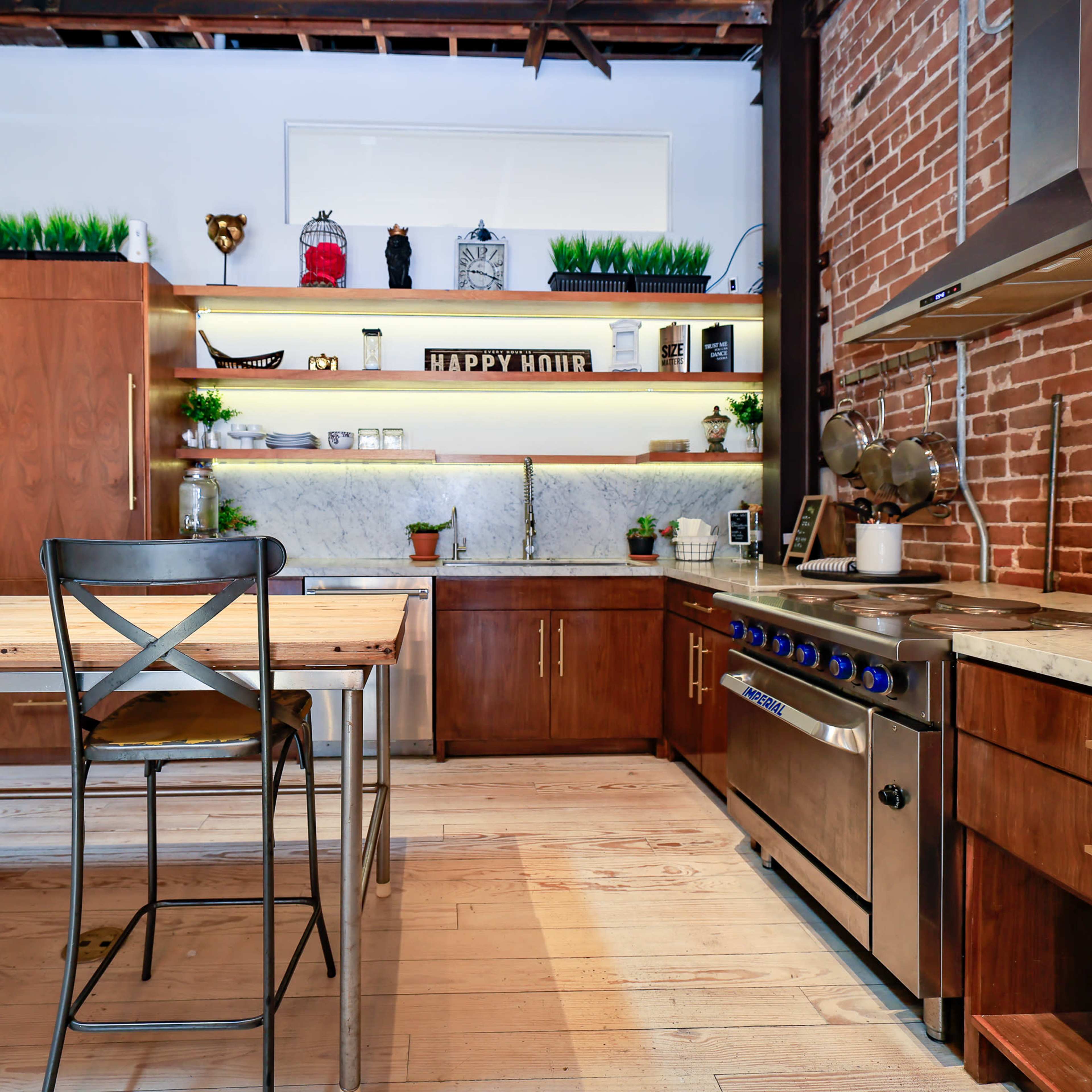 The kitchen features wood cabinetry, metal appliances, and a central wooden table with an industrial-style chair.