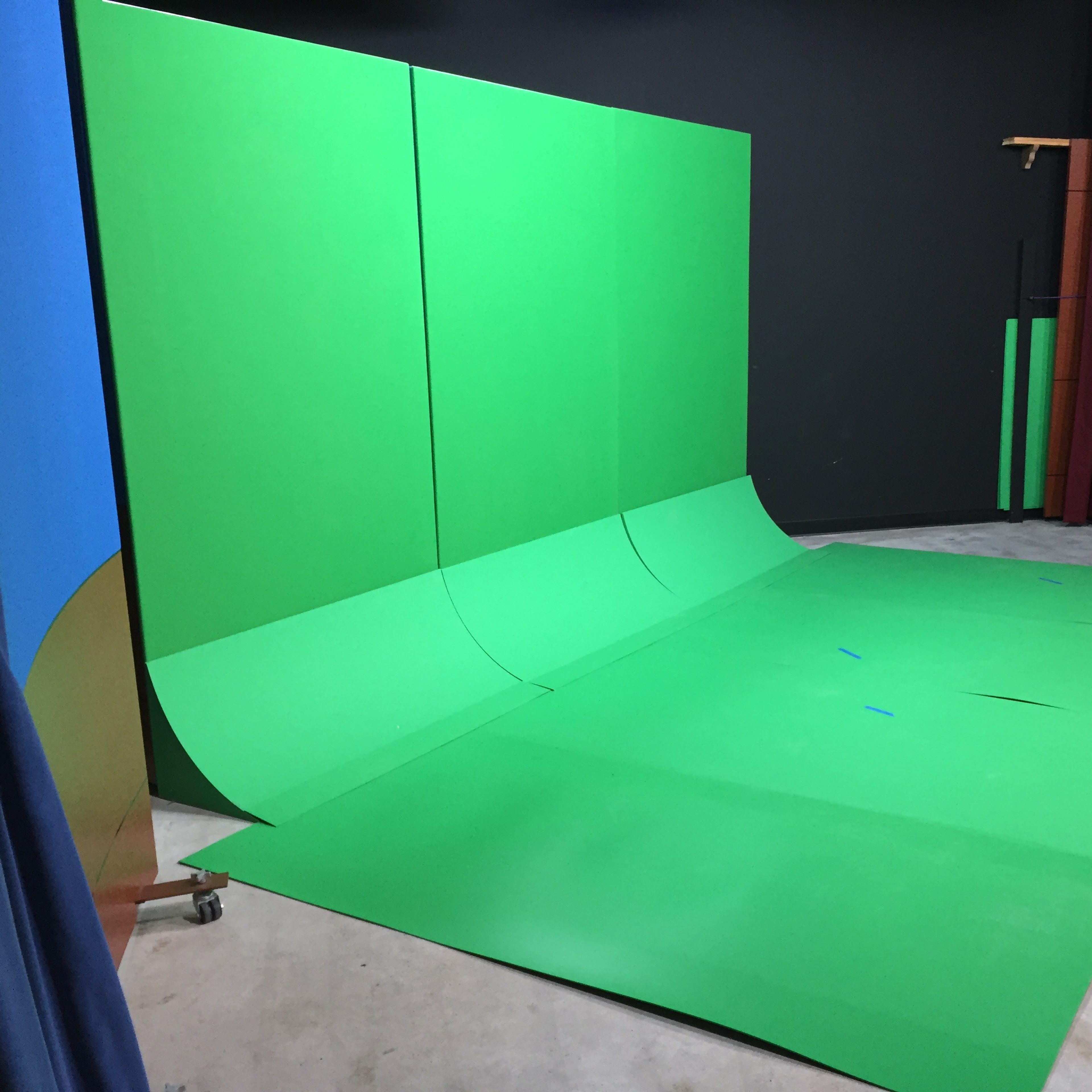 A studio setup featuring a large green screen backdrop and a matching green floor.