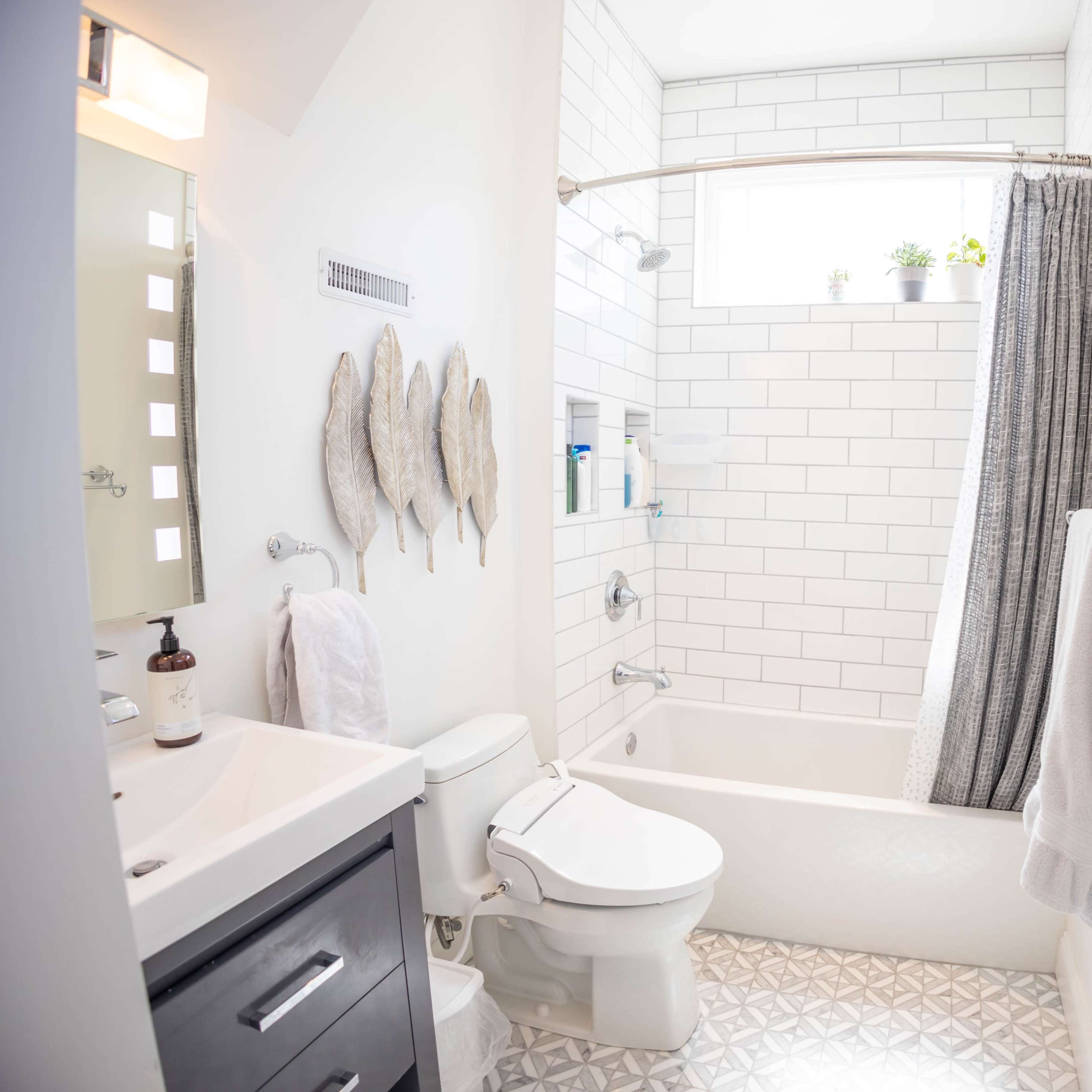A modern bathroom with a bathtub, gray shower curtain, and white tiled walls.