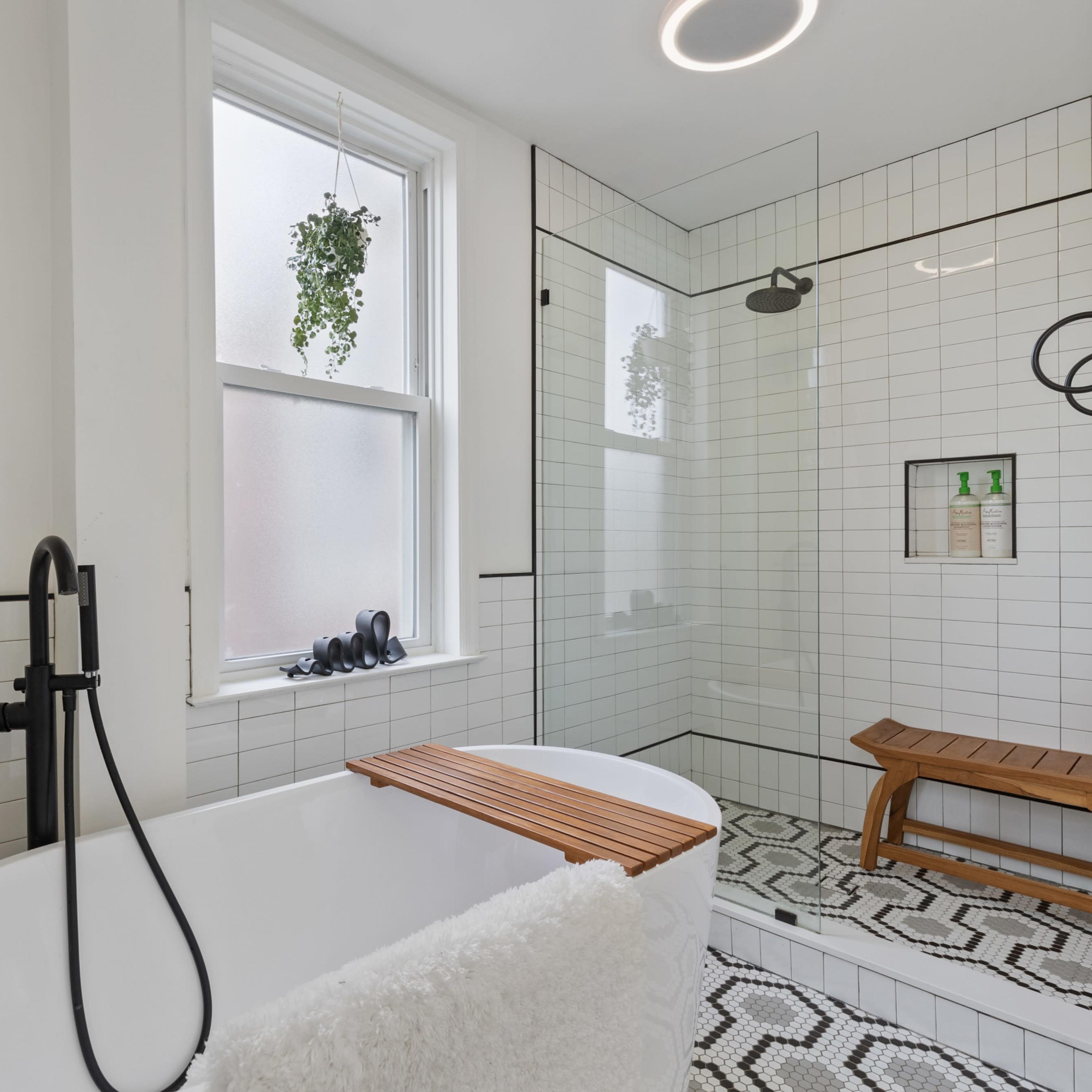 A modern bathroom with a freestanding bathtub, a walk-in shower with glass walls, and tiled flooring featuring a geometric pattern.