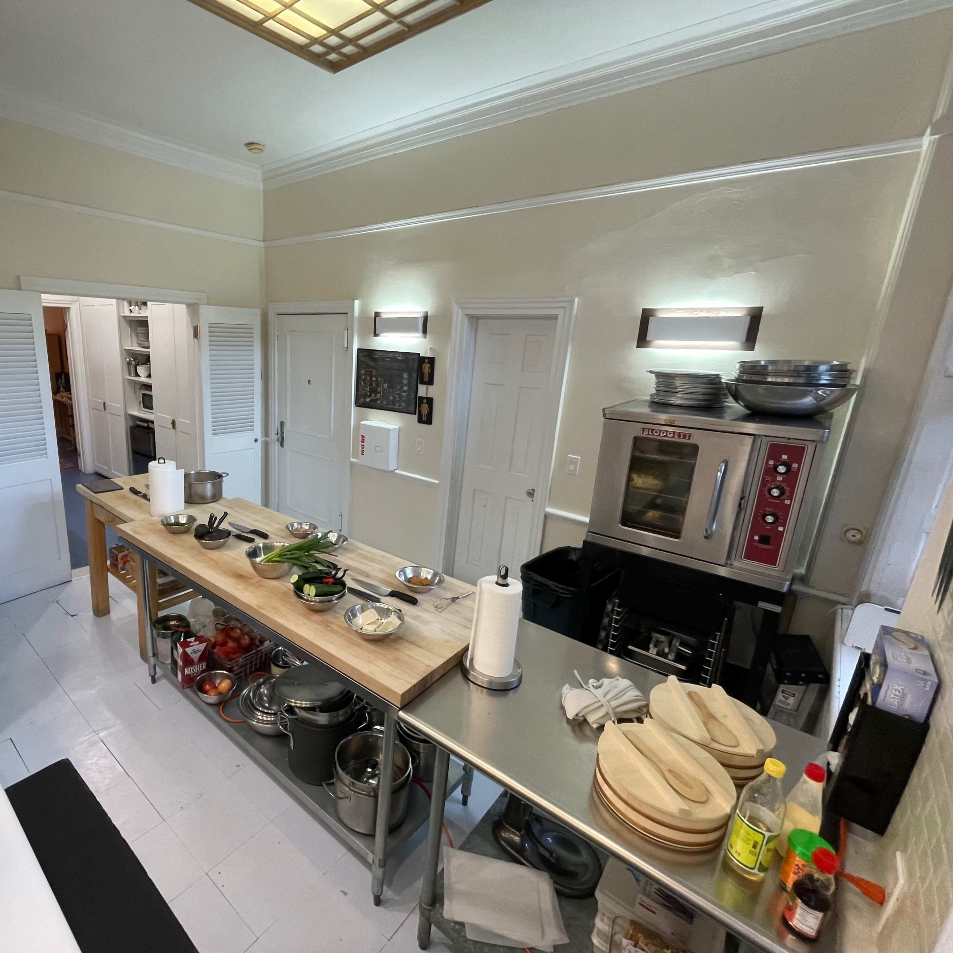 A spacious kitchen with stainless steel tables, cabinets, and various culinary tools neatly arranged throughout.