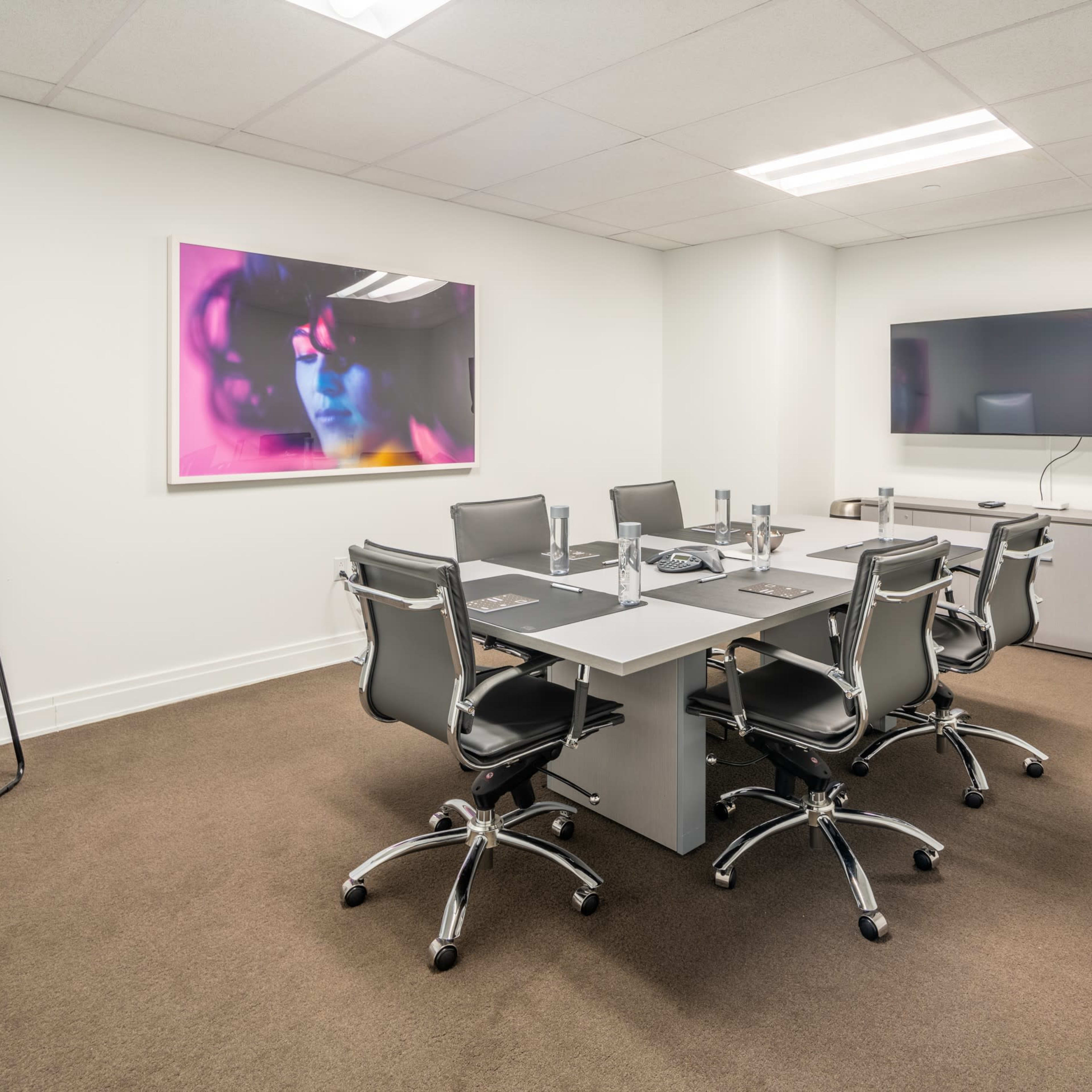 A modern conference room with a rectangular table surrounded by six chairs, a whiteboard, and a television mounted on the wall.