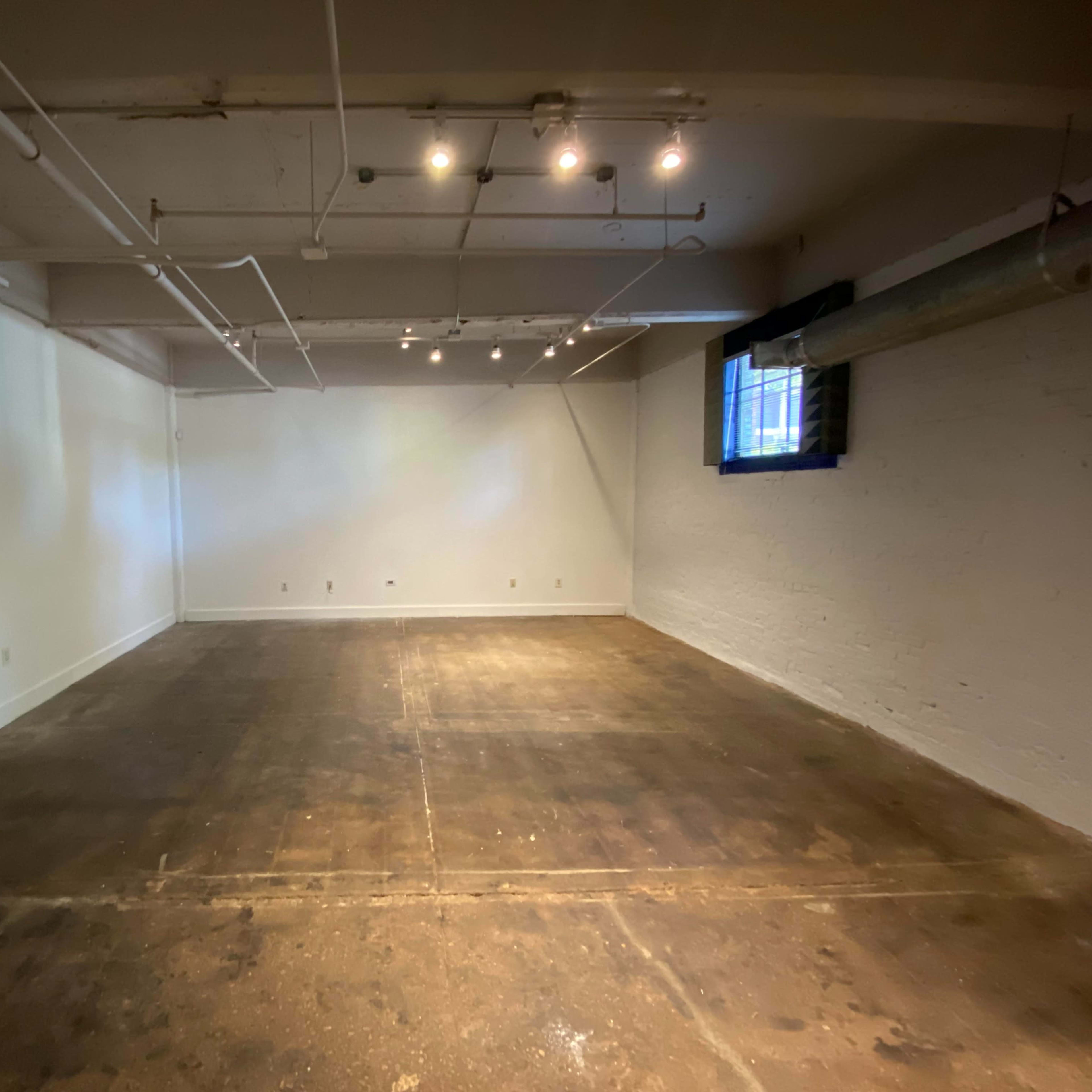An empty, well-lit room with concrete flooring and white walls.
