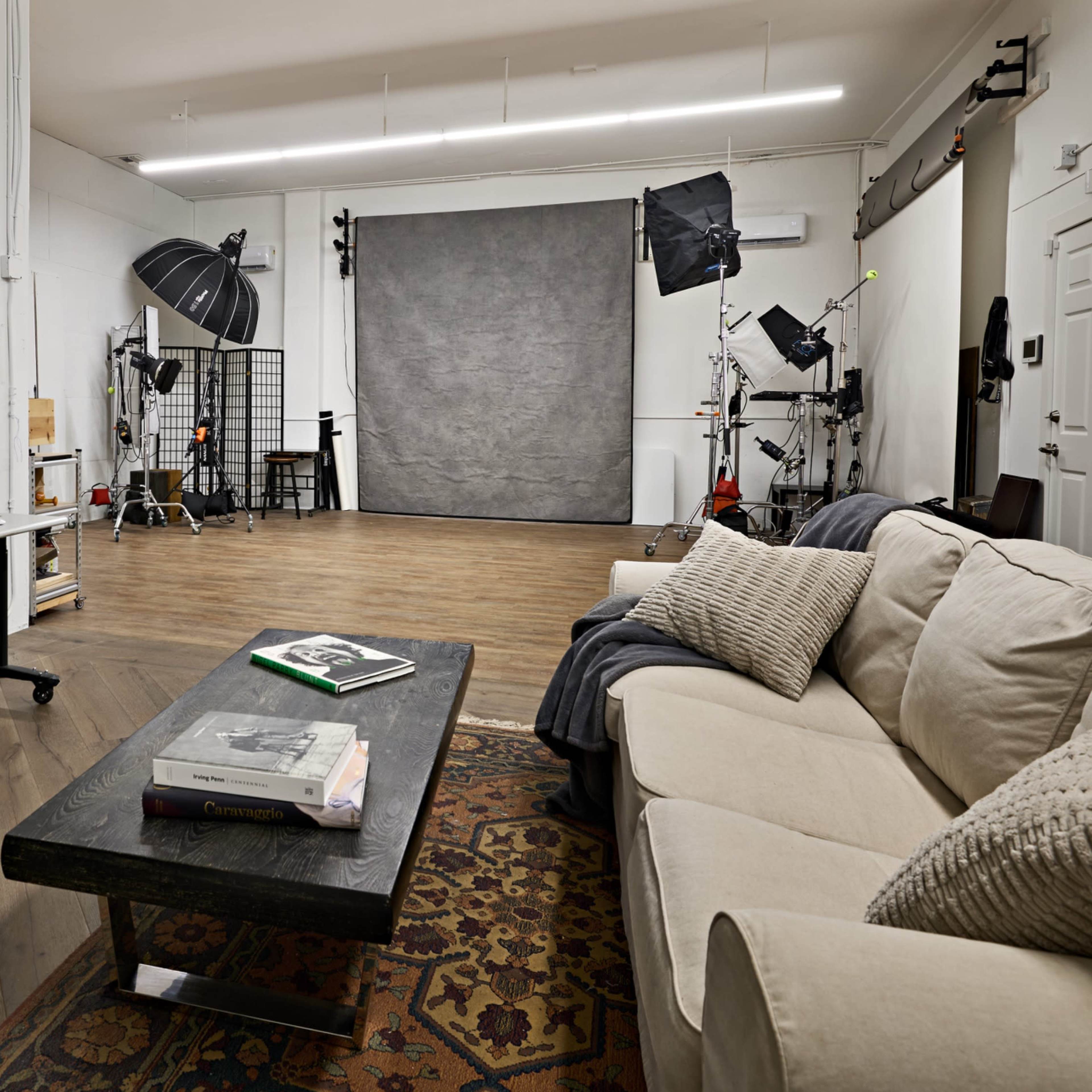 A photography studio with a seating area, work desk, and backdrop setup.