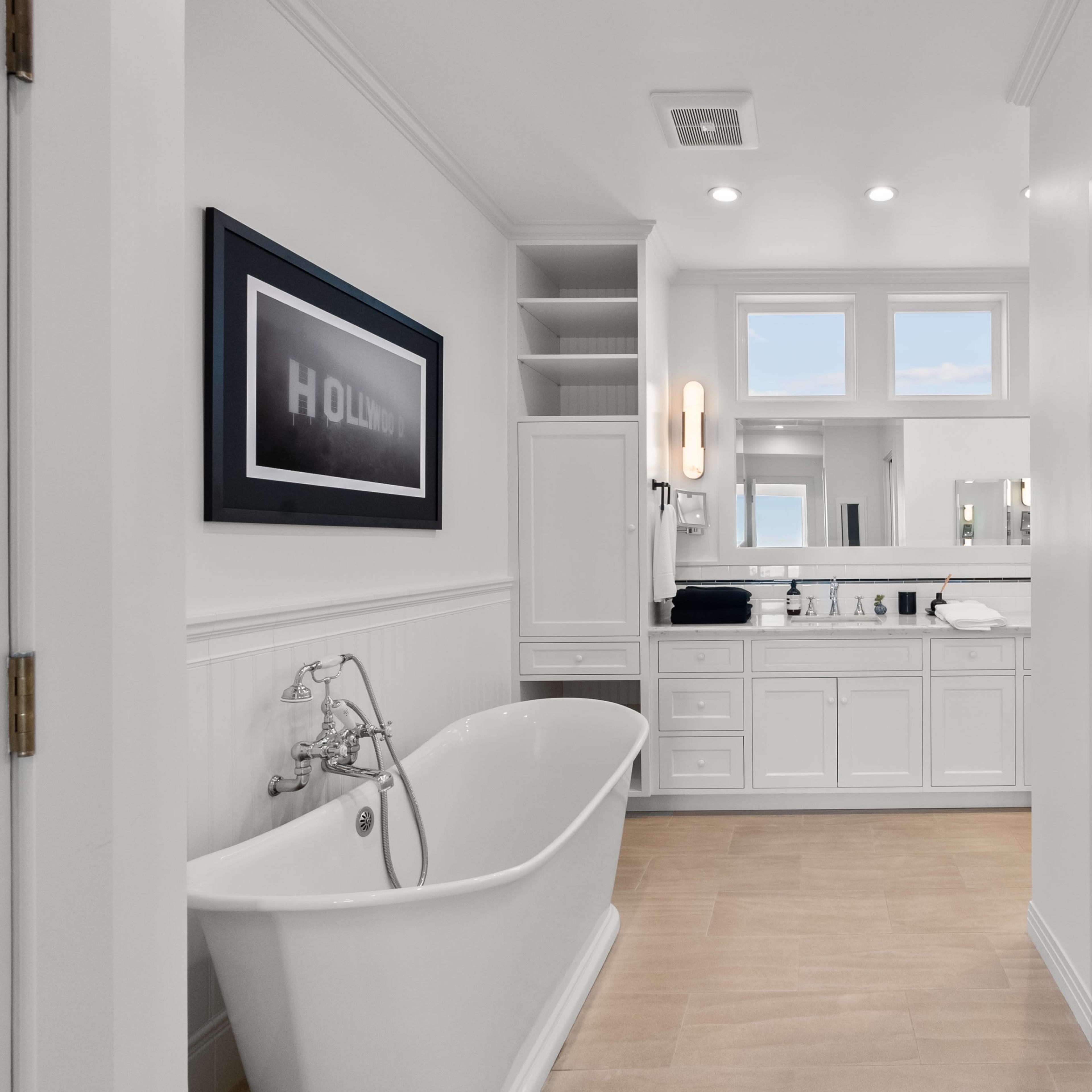 A spacious bathroom features a freestanding bathtub, double sinks, and modern cabinetry, with natural light highlighting the clean design.