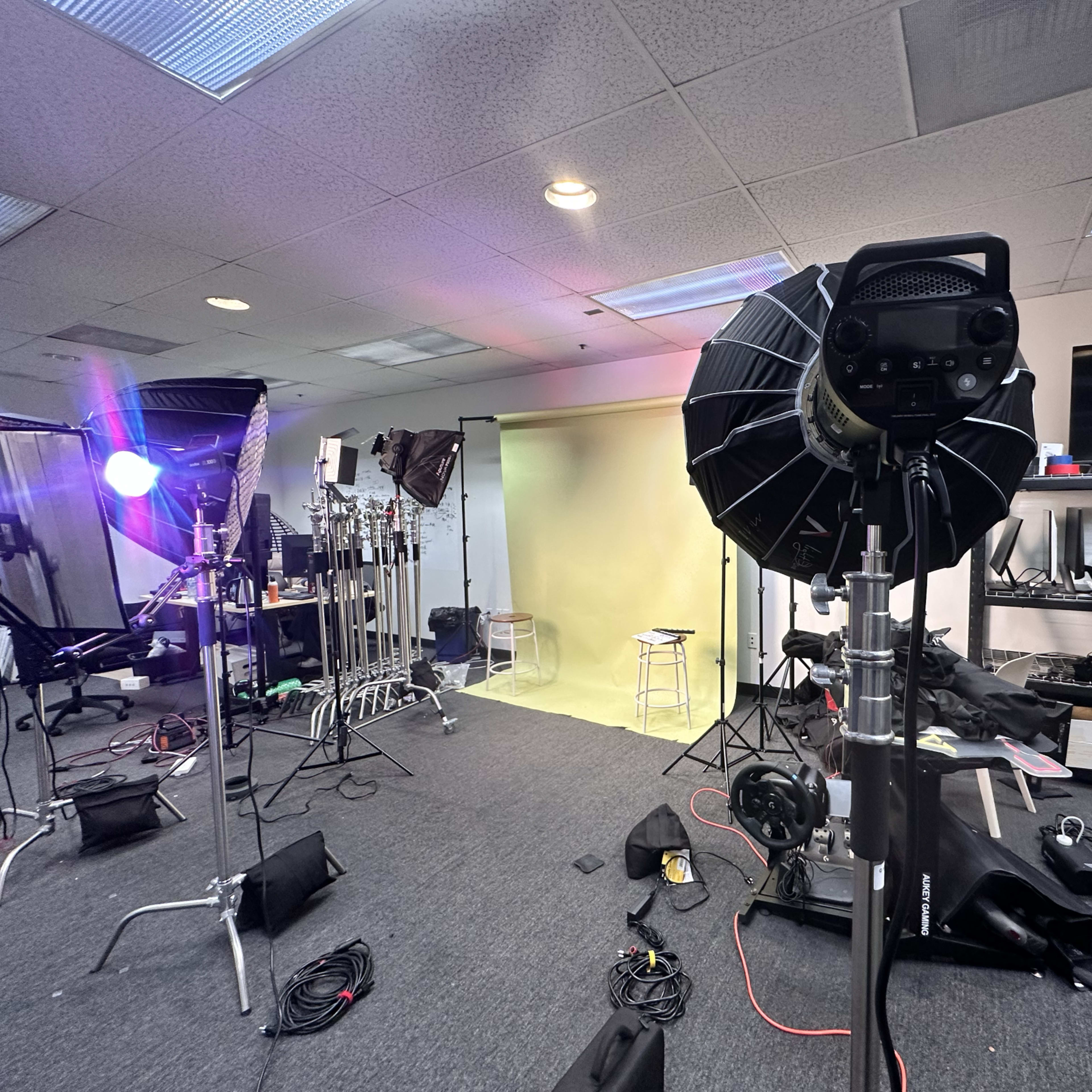 A photography studio set up with multiple lights, a backdrop, and various equipment arranged around the space.