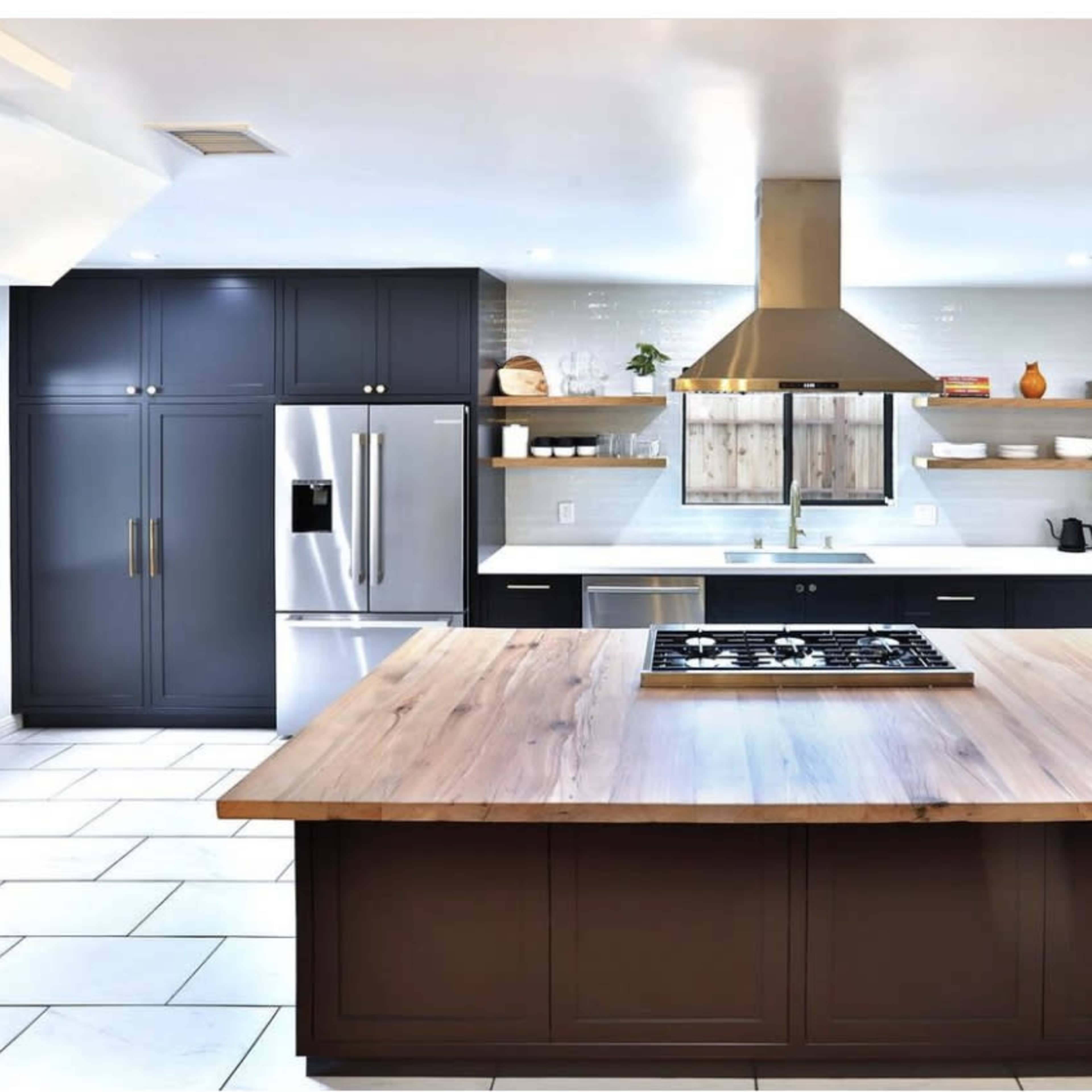 The kitchen features a large wooden island with a gas cooktop, dark cabinetry, stainless steel appliances, and open shelving.