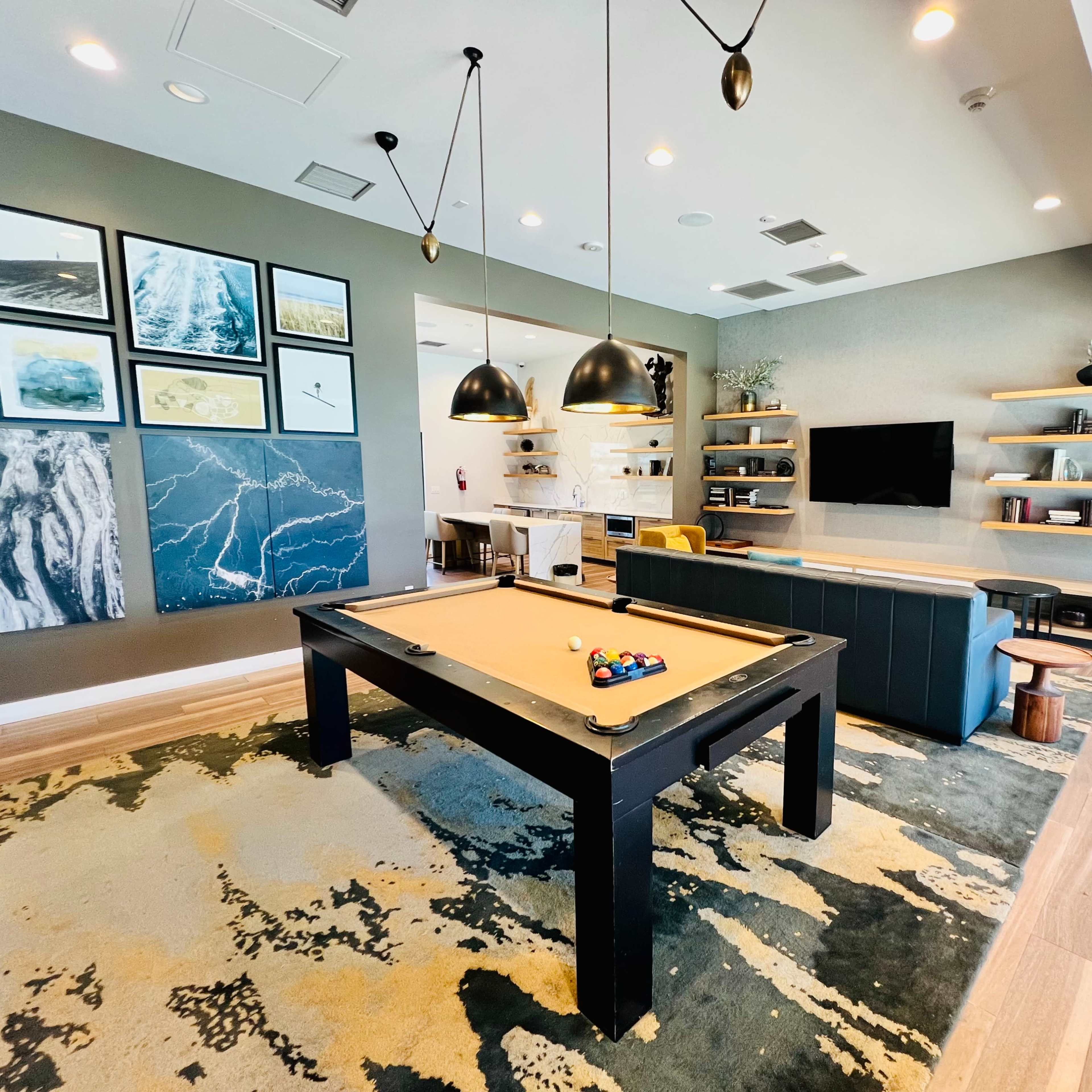 A game room with a pool table, modern seating, a television, and decorative wall art.