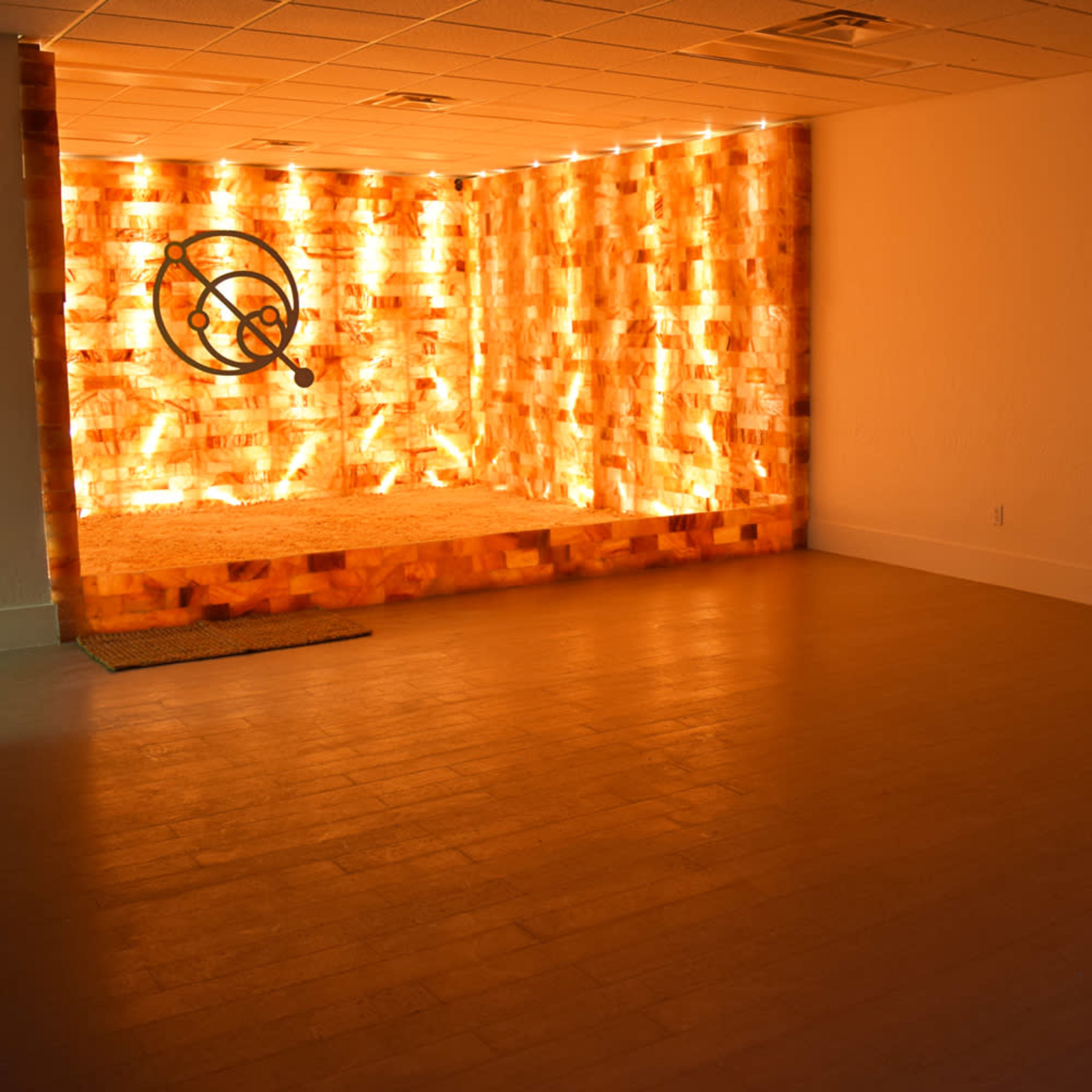 A well-lit room with a wall made of illuminated salt bricks and a television displaying a close-up of cooking ingredients.