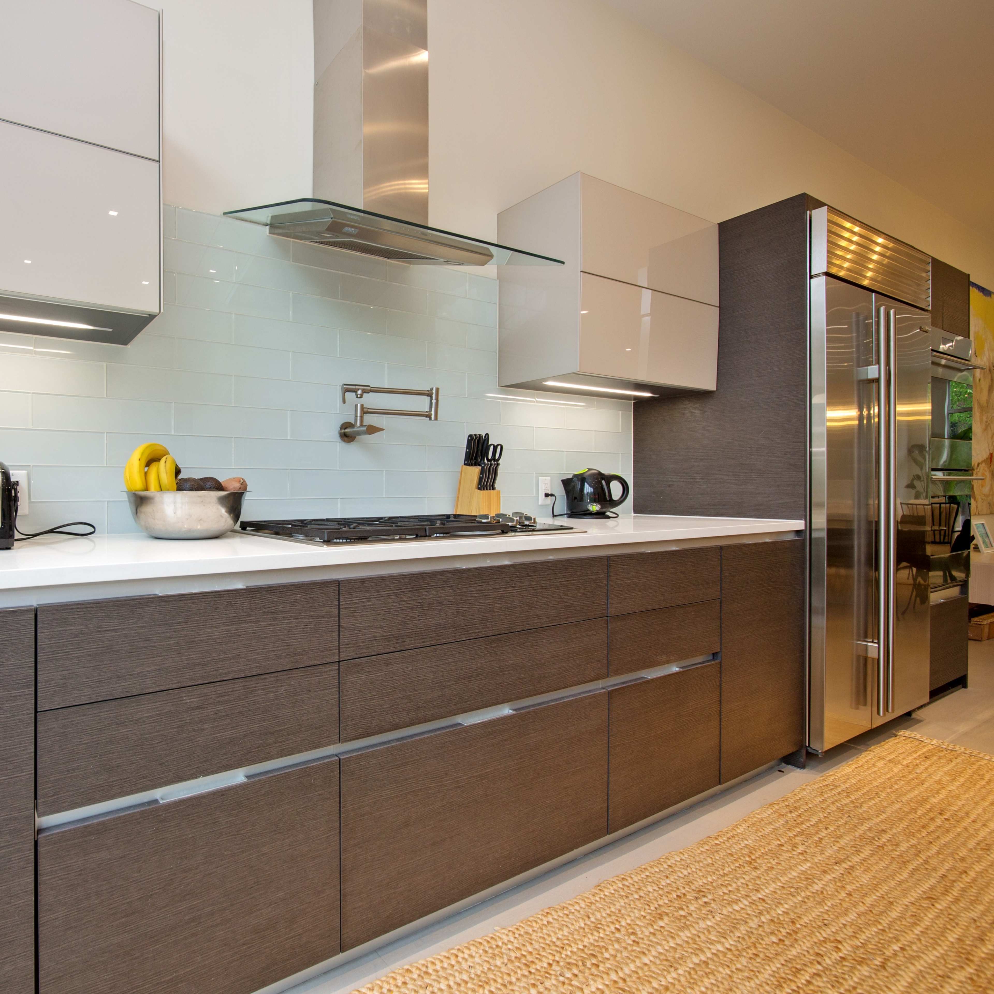 A modern kitchen featuring sleek cabinetry, a stainless steel refrigerator, a gas stove, and a blender on the countertop.