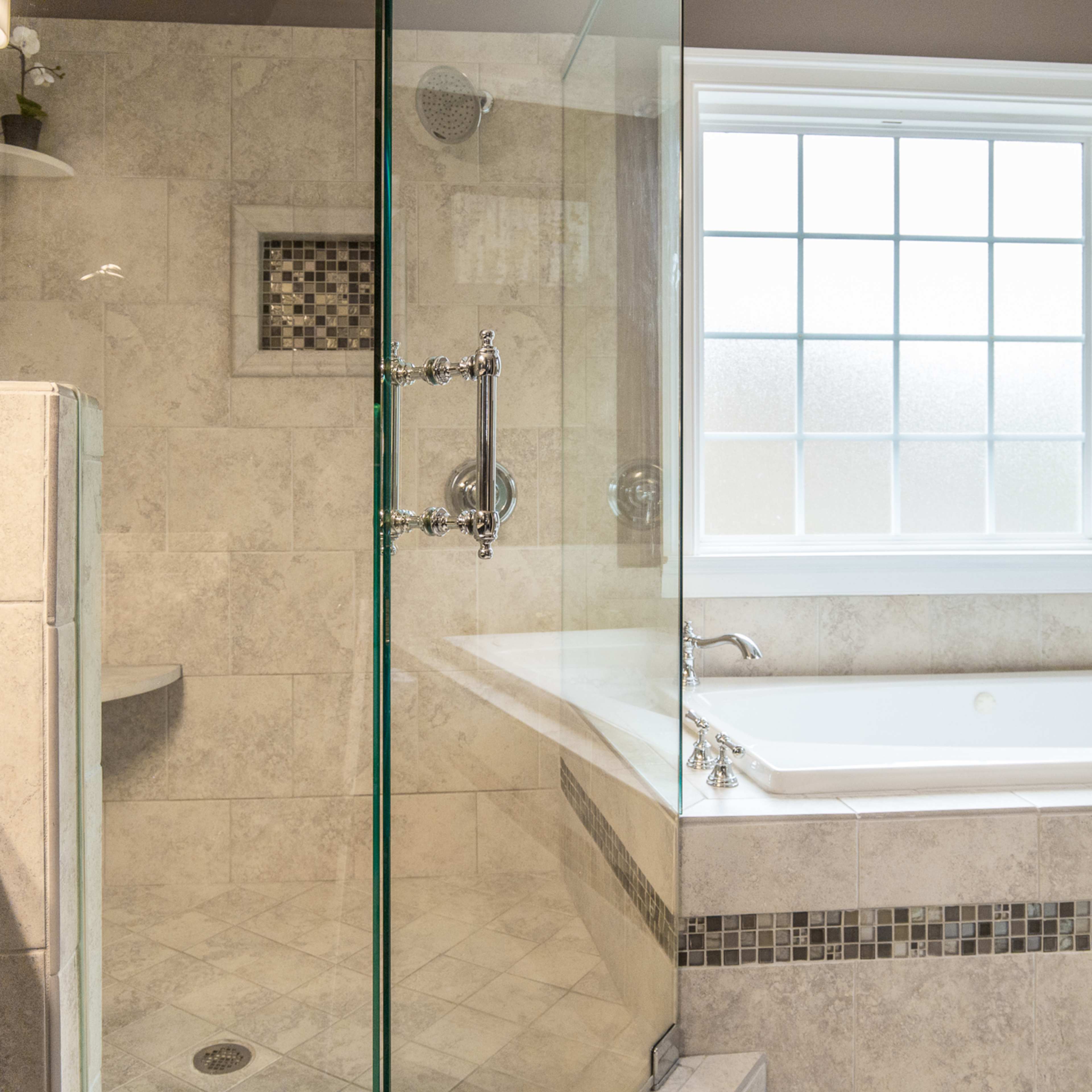 A modern bathroom featuring a glass shower enclosure, a freestanding bathtub, and a large window allowing natural light.