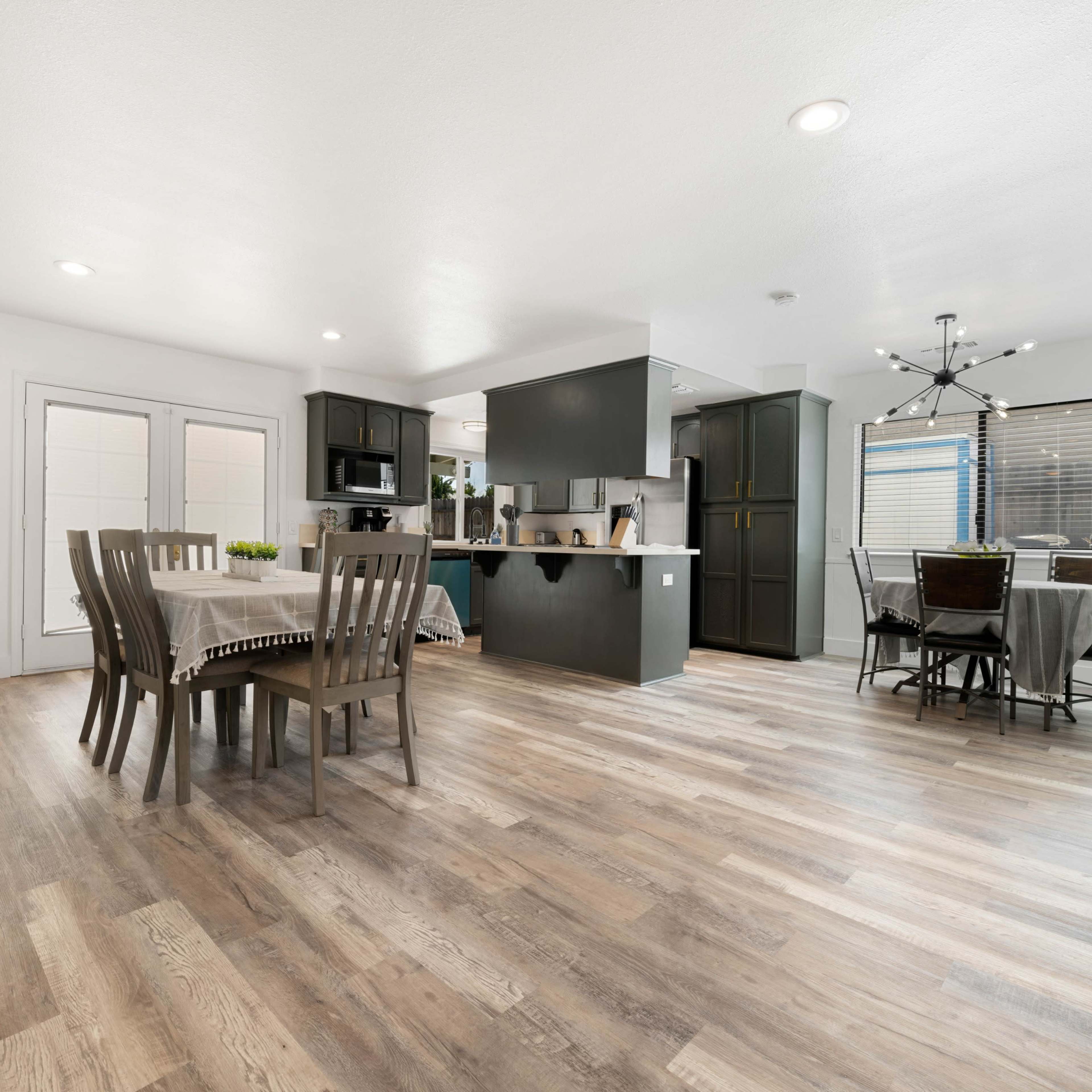 A modern open-concept kitchen and dining area with light wooden flooring and a table set for dining.