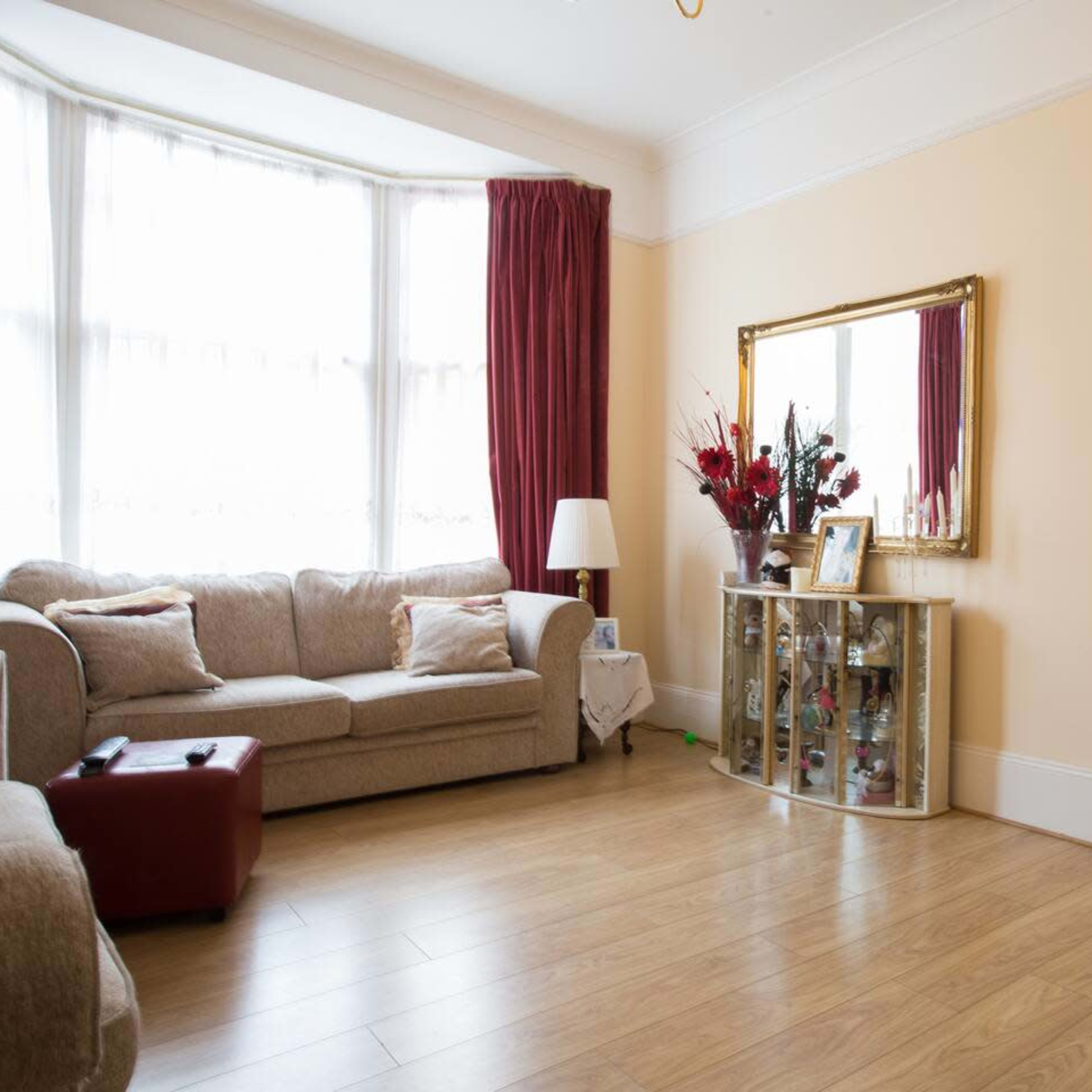 A living room with a light-colored sofa, a decorative mirror on the wall, and a doorway leading to a dining area.