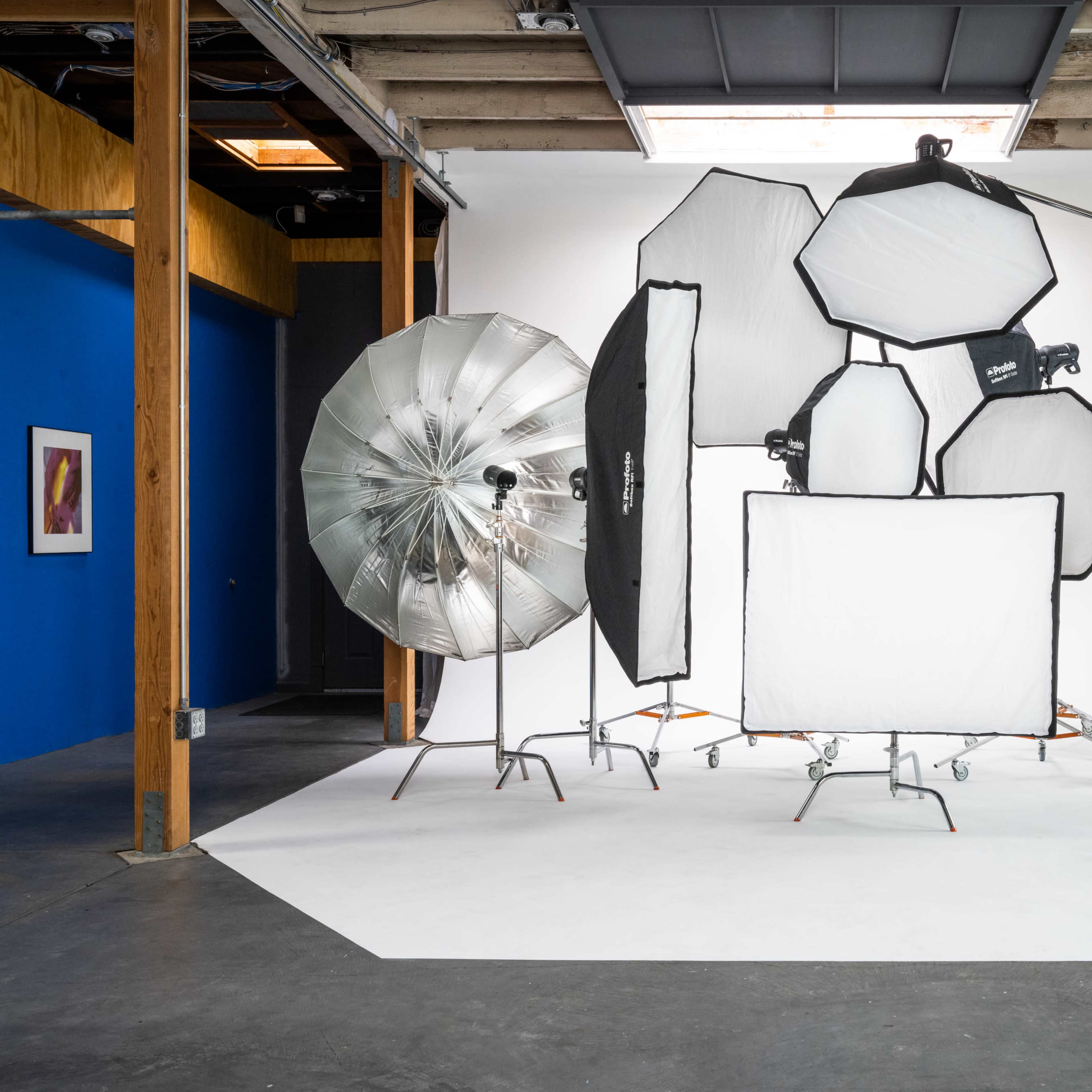 A photography studio setup featuring various lighting equipment, including softboxes and reflectors, arranged against a white backdrop.