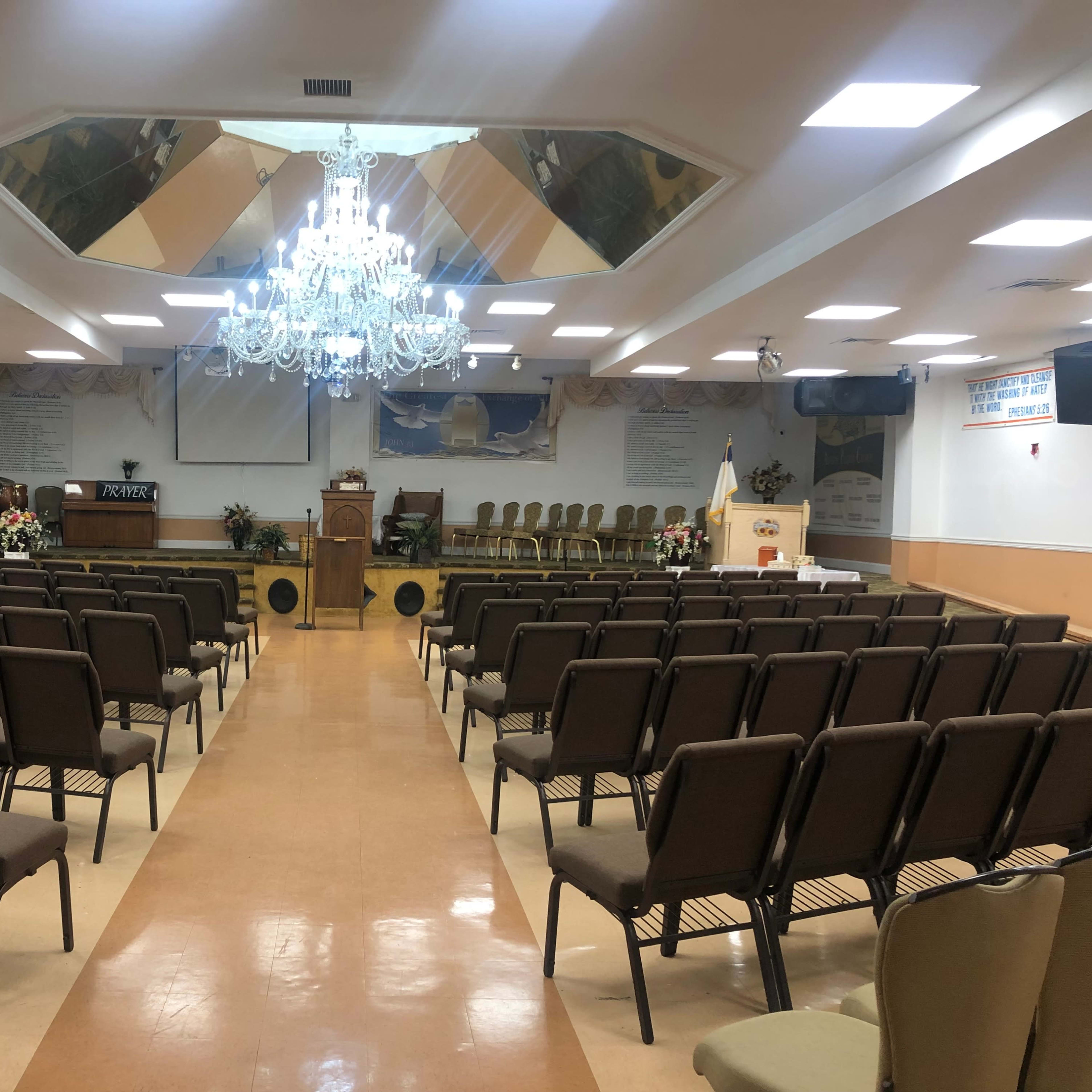 A spacious, empty auditorium with rows of chairs facing a stage adorned with a podium and decorative elements.