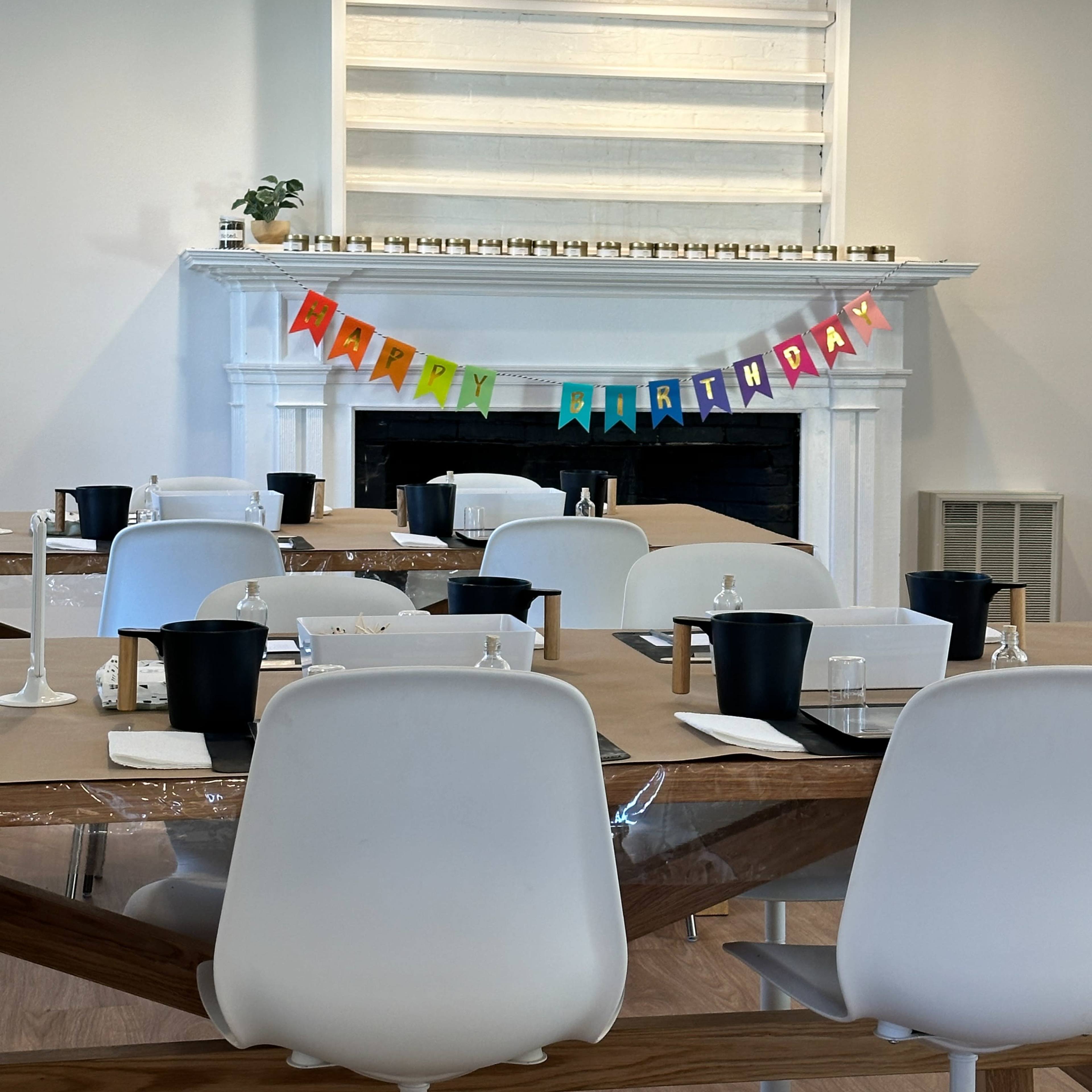The room features a large table set for a birthday celebration, with a colorful "Happy Birthday" banner displayed above a decorative fireplace.