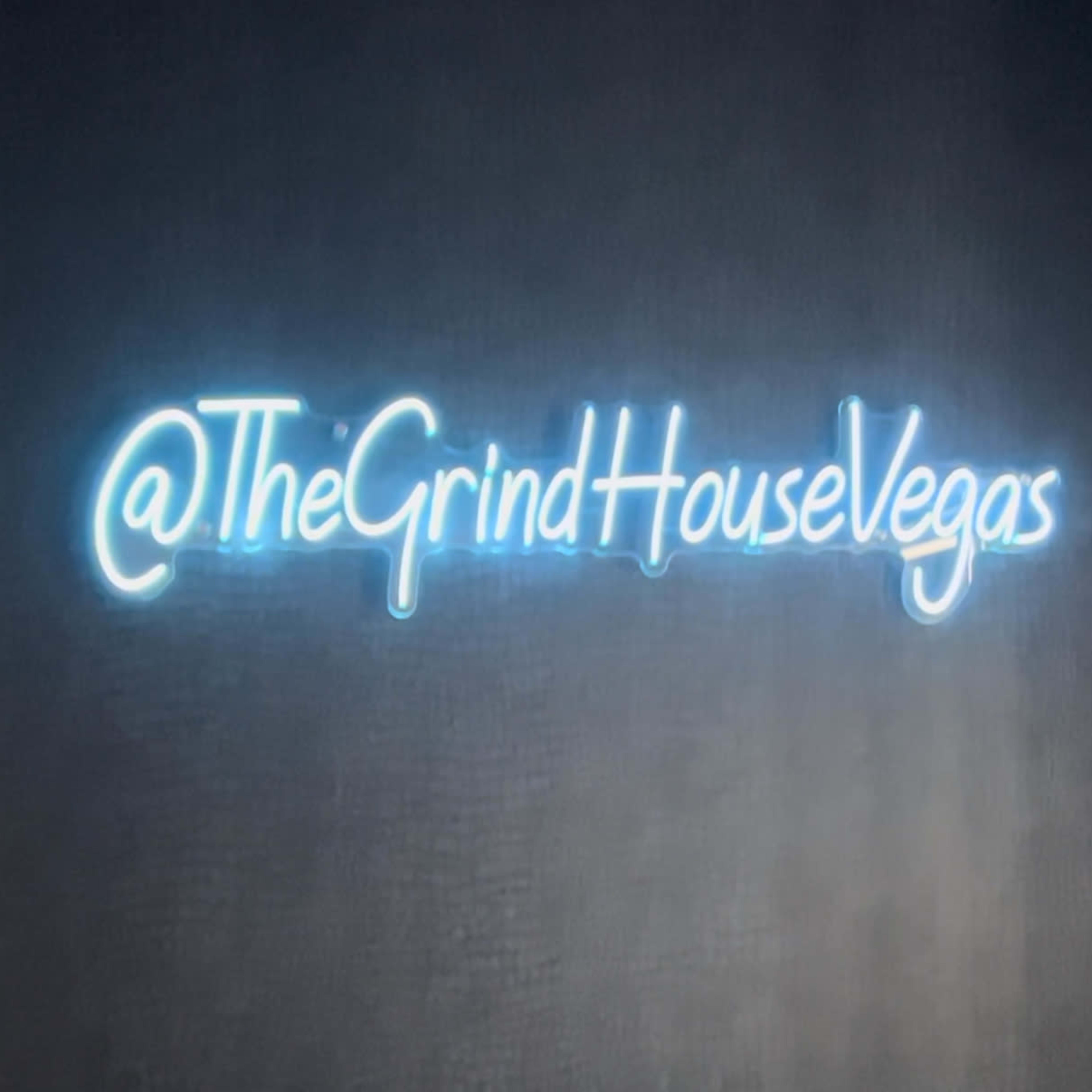 A glowing neon sign that displays the text "@TheGrindHouseVegas."