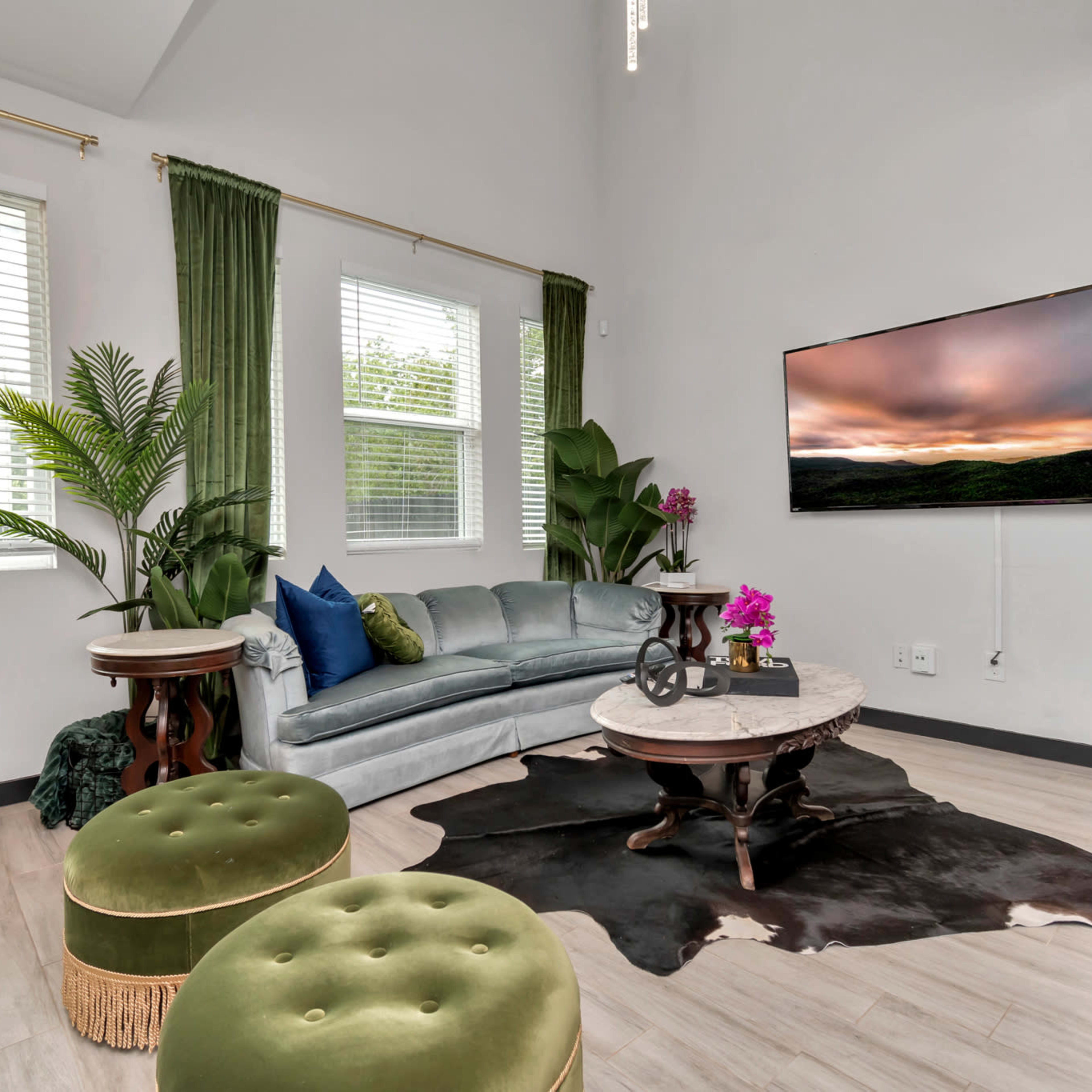 A modern living room with a sectional sofa, a round coffee table, a bar cart, and green curtains.