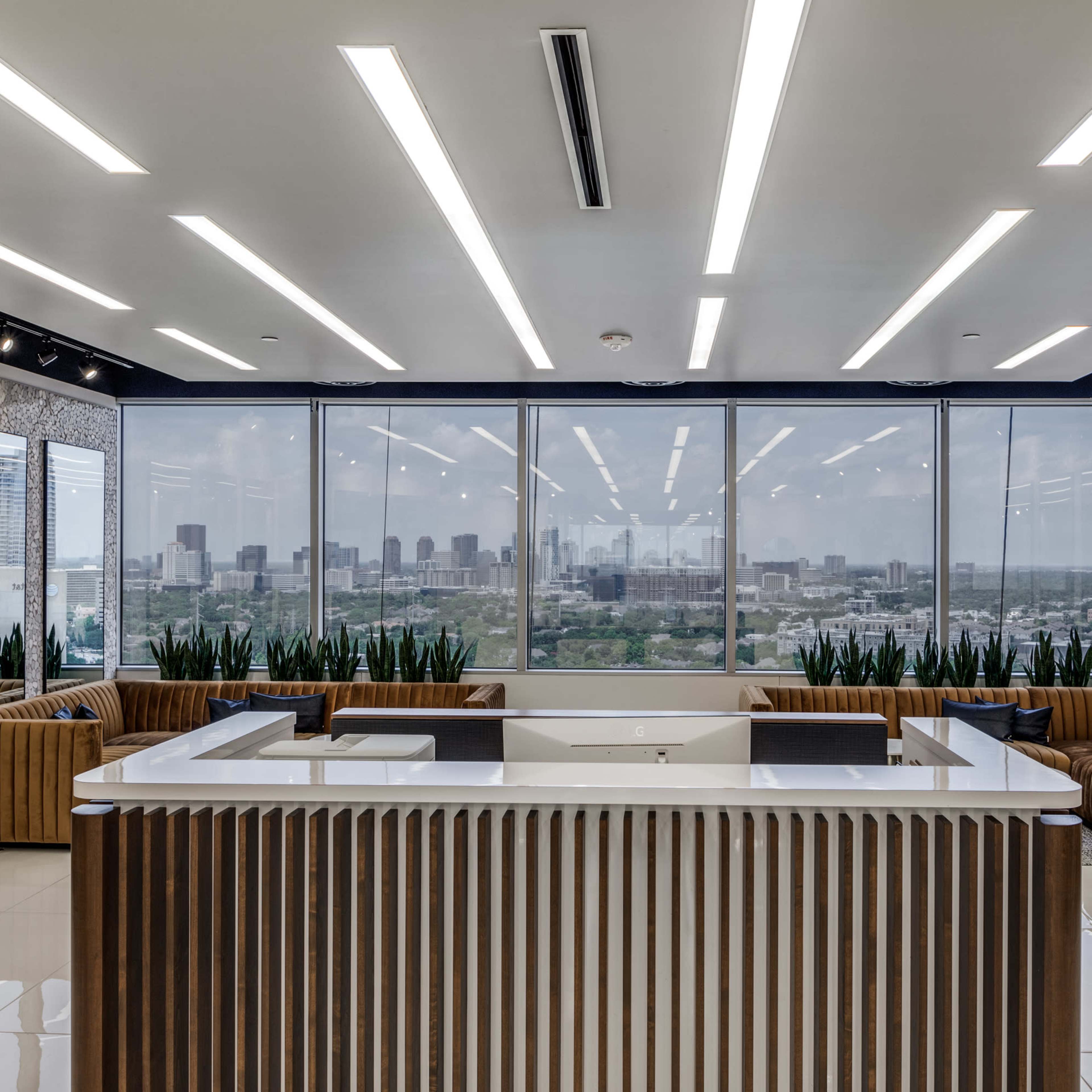 A modern office reception area featuring a sleek white counter and large windows showcasing a city skyline.