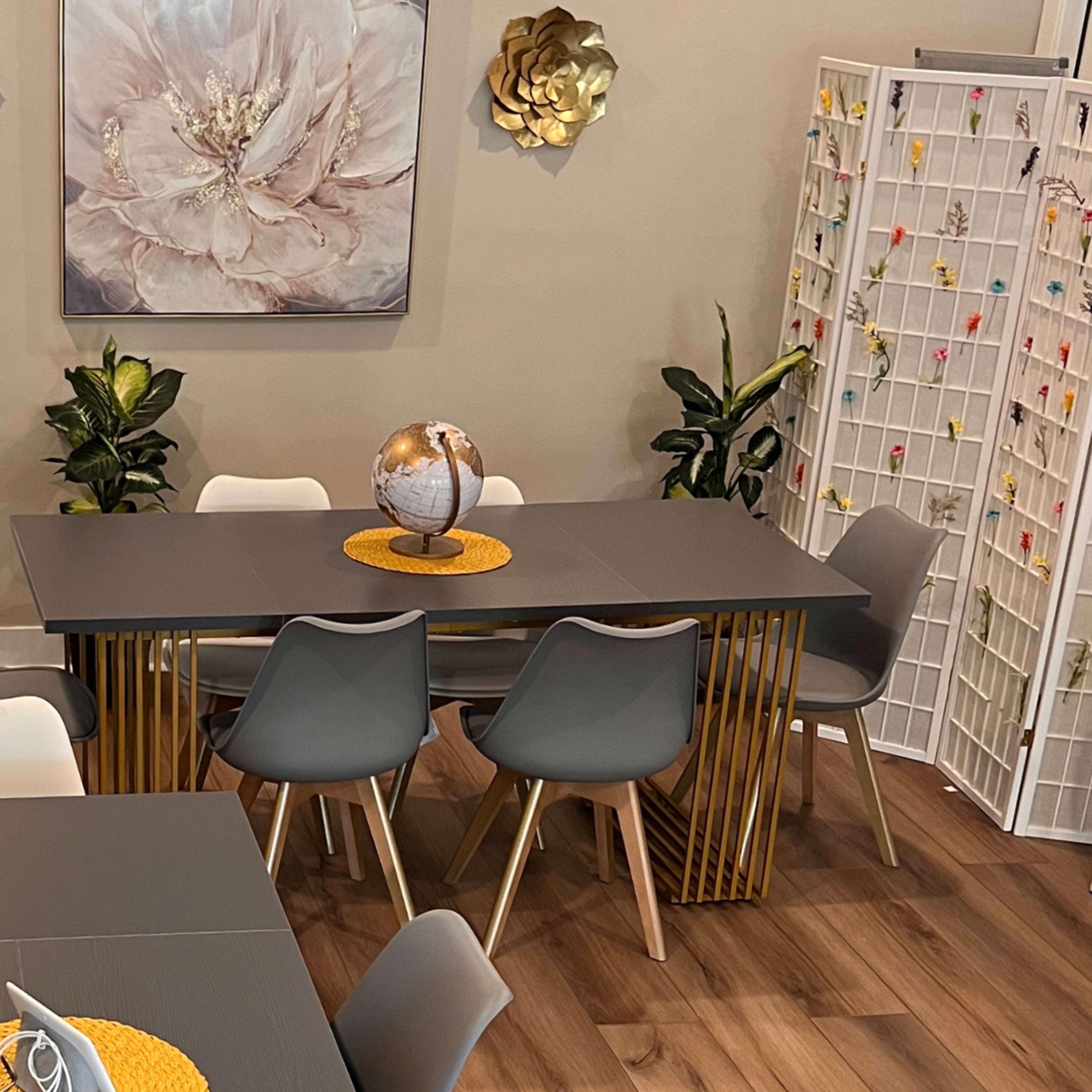 A modern dining area features a large table surrounded by various chairs, a globe centerpiece, and decorative wall art.