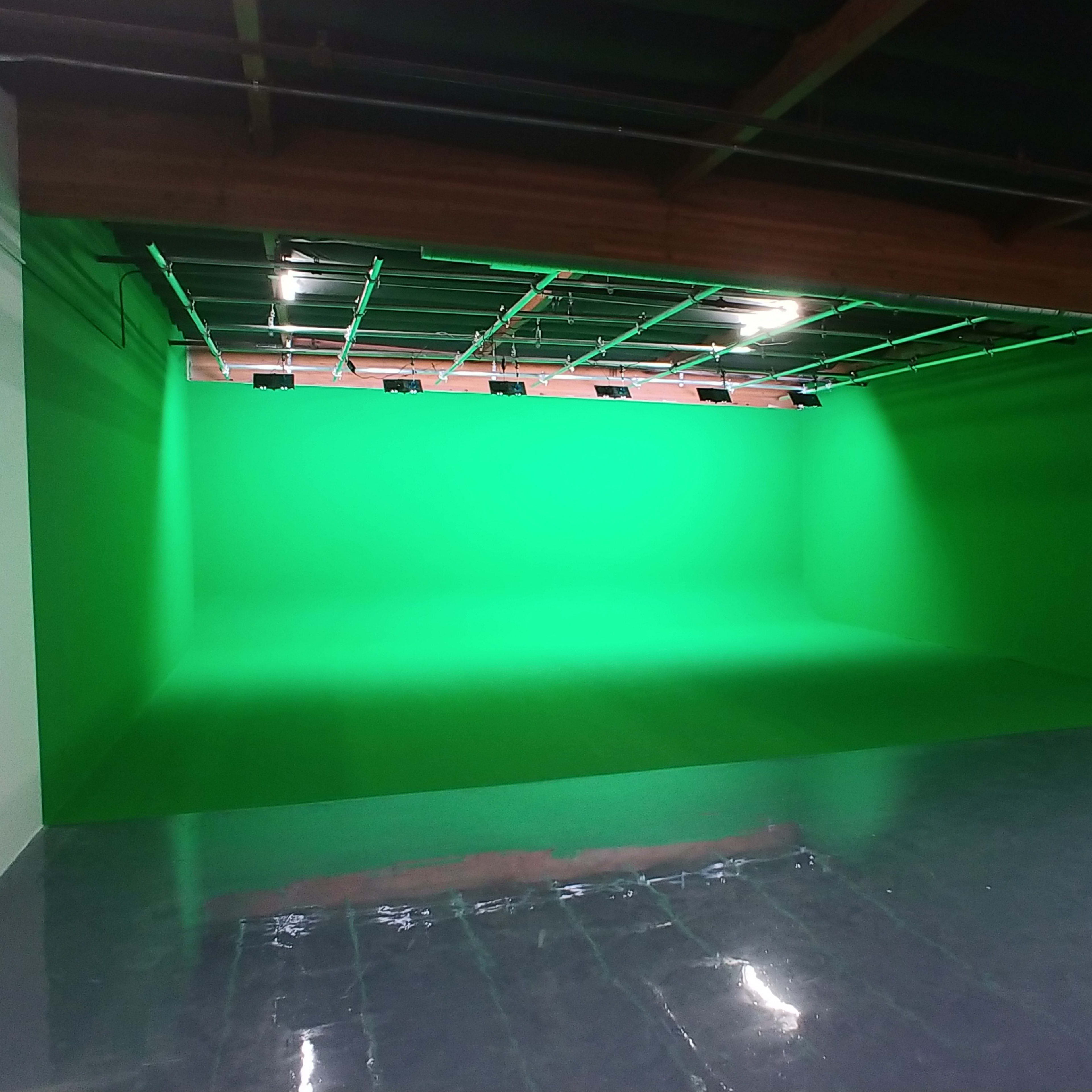 A large room with a bright green backdrop and polished concrete flooring.