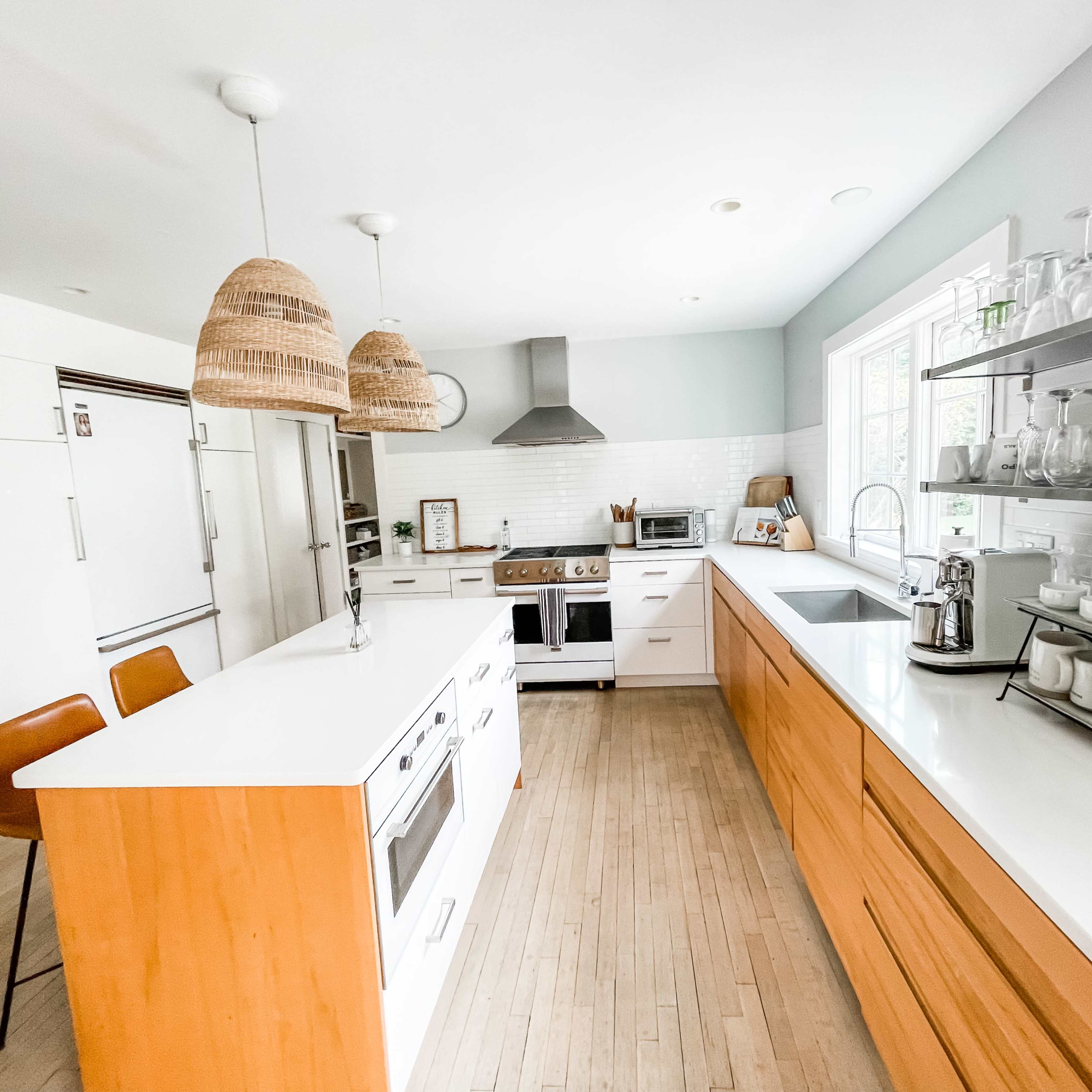 The kitchen features wooden cabinetry, a central island with a sink, modern appliances, and rattan pendant lights.