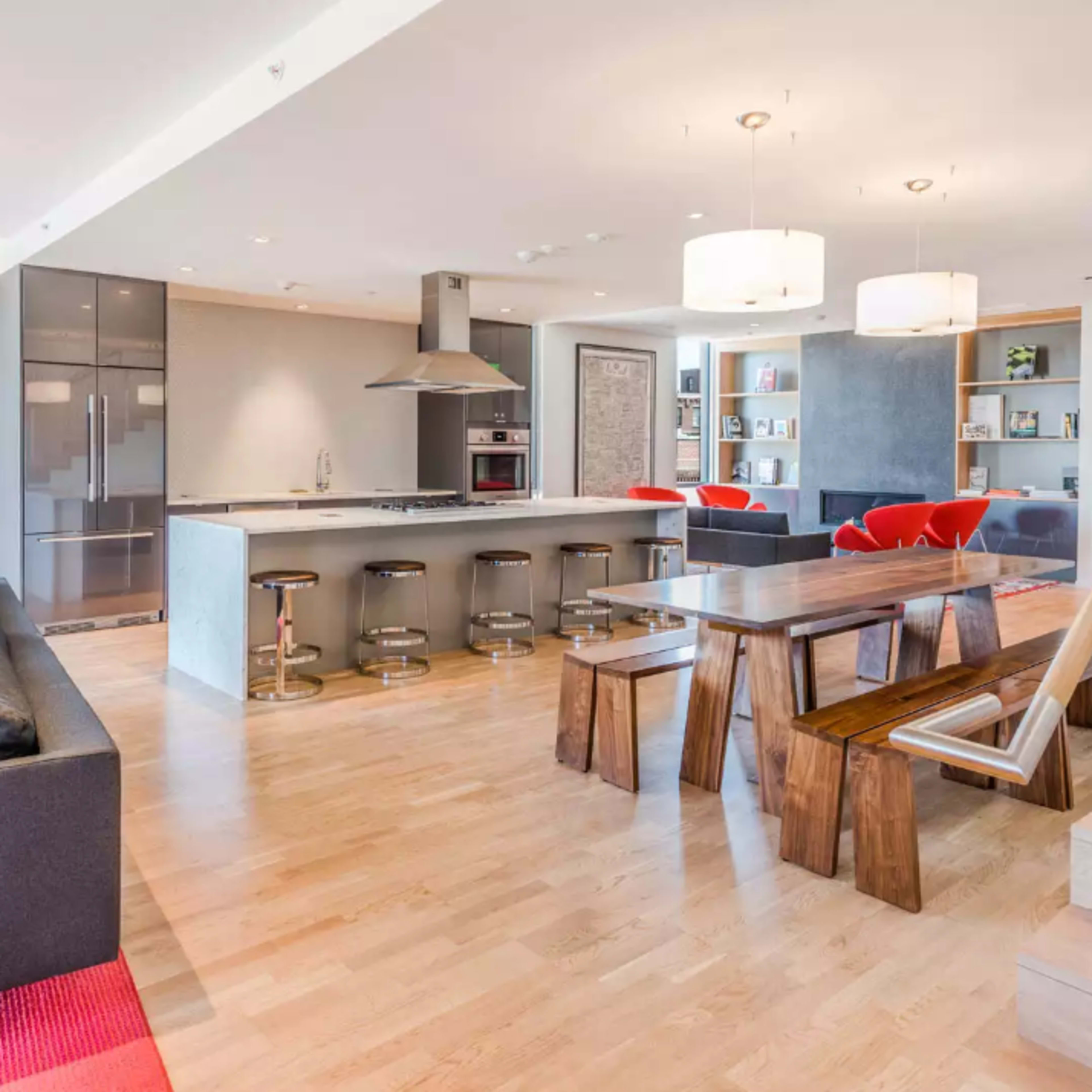 A modern open-concept living space featuring a kitchen with a large island, a dining table made of wood, and a staircase leading to an upper level.