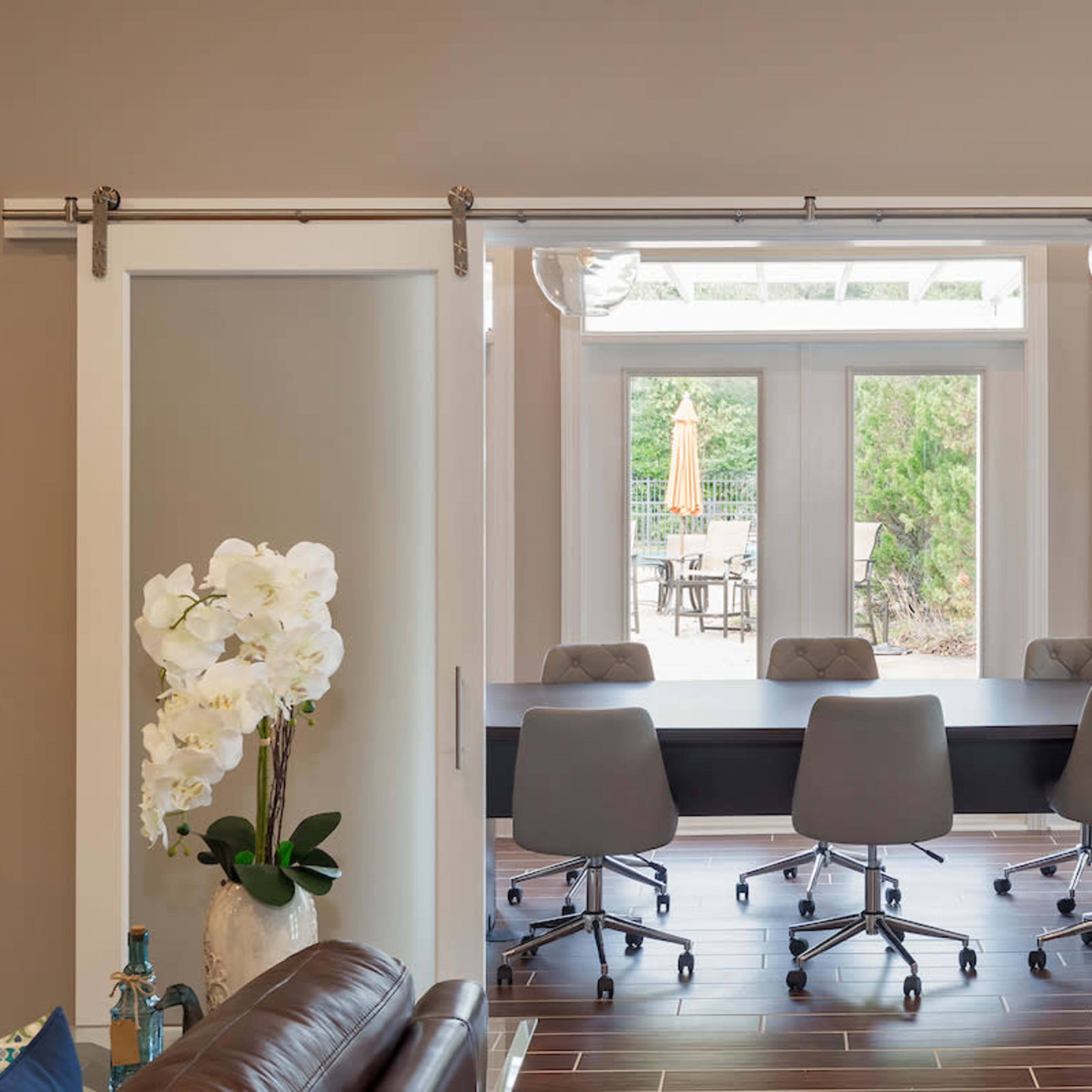 A spacious conference room is visible through sliding glass doors, featuring a long table and several ergonomic chairs.