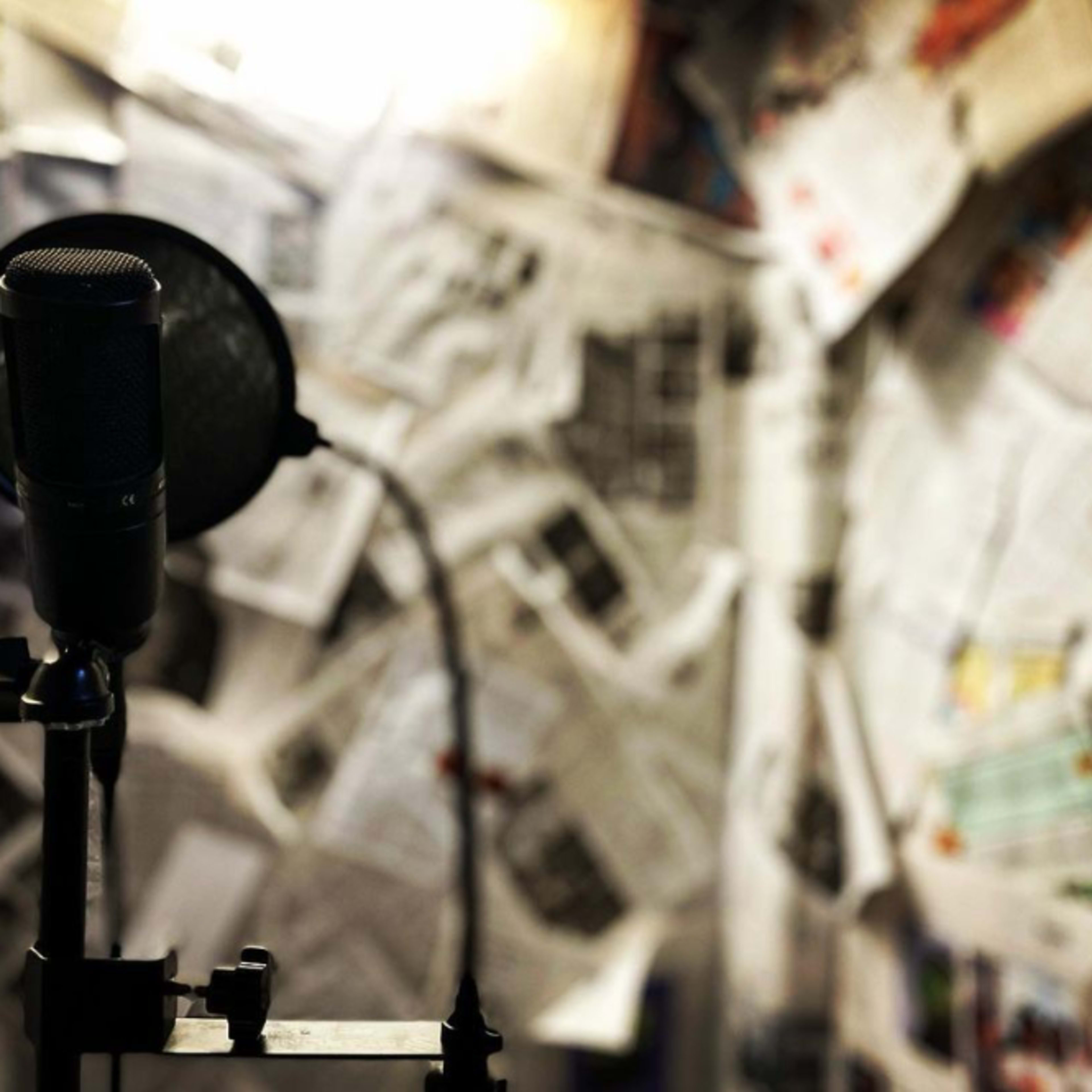 A microphone stands in front of a wall covered with newspapers.