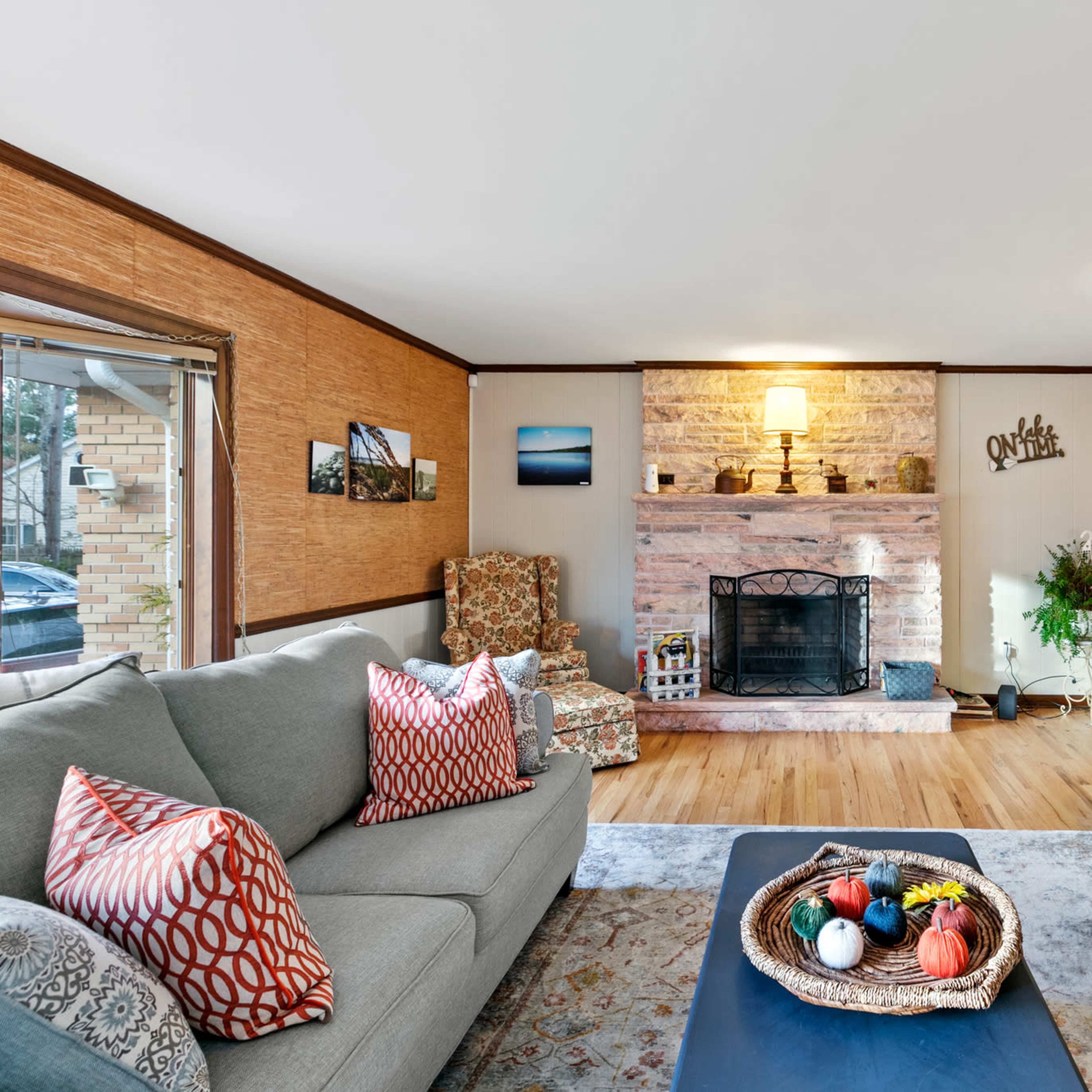 A cozy living room features a stone fireplace, two sofas, and decorative elements on a wooden floor.