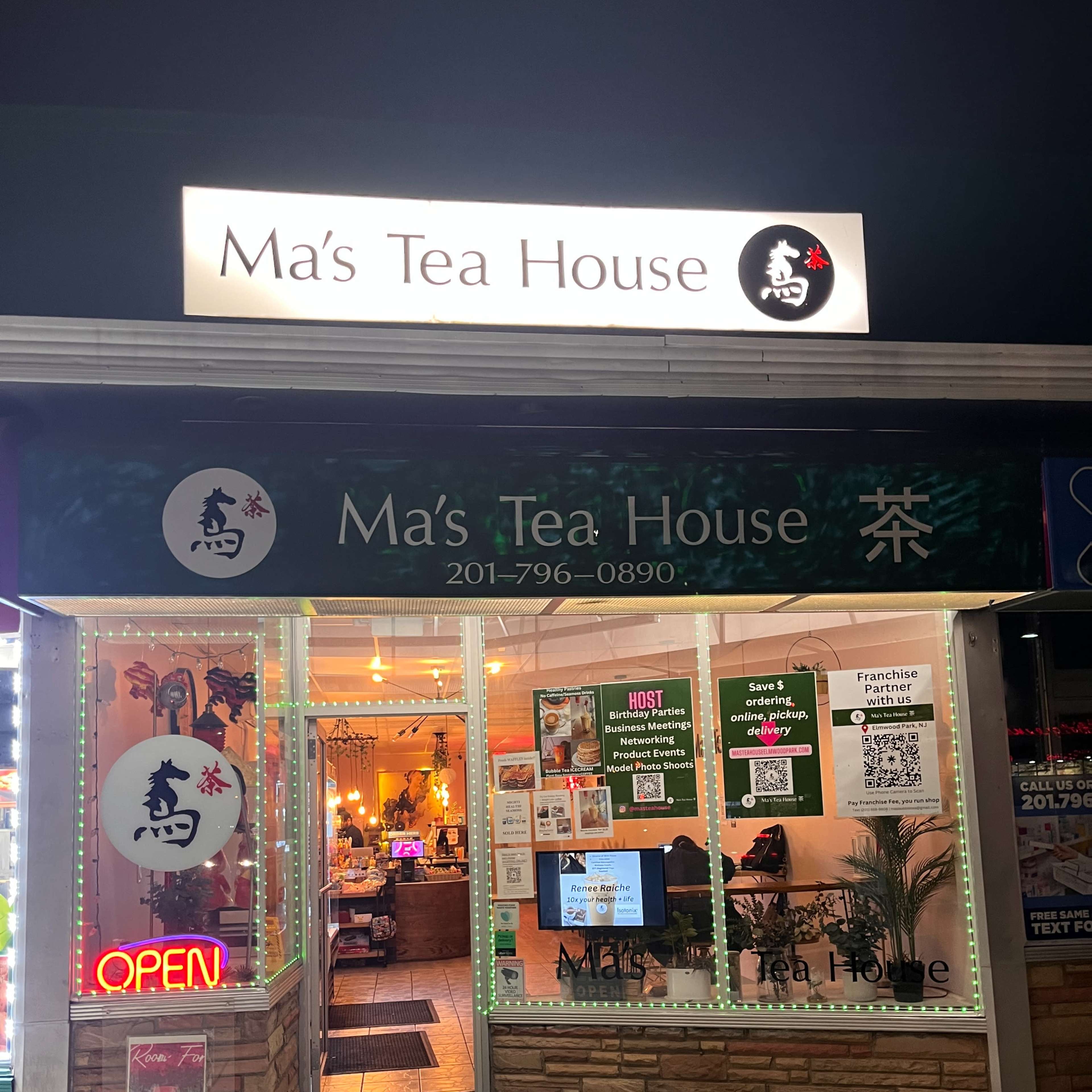 The storefront of Ma's Tea House features bright signage and an illuminated open sign, showcasing a welcoming entrance at night.