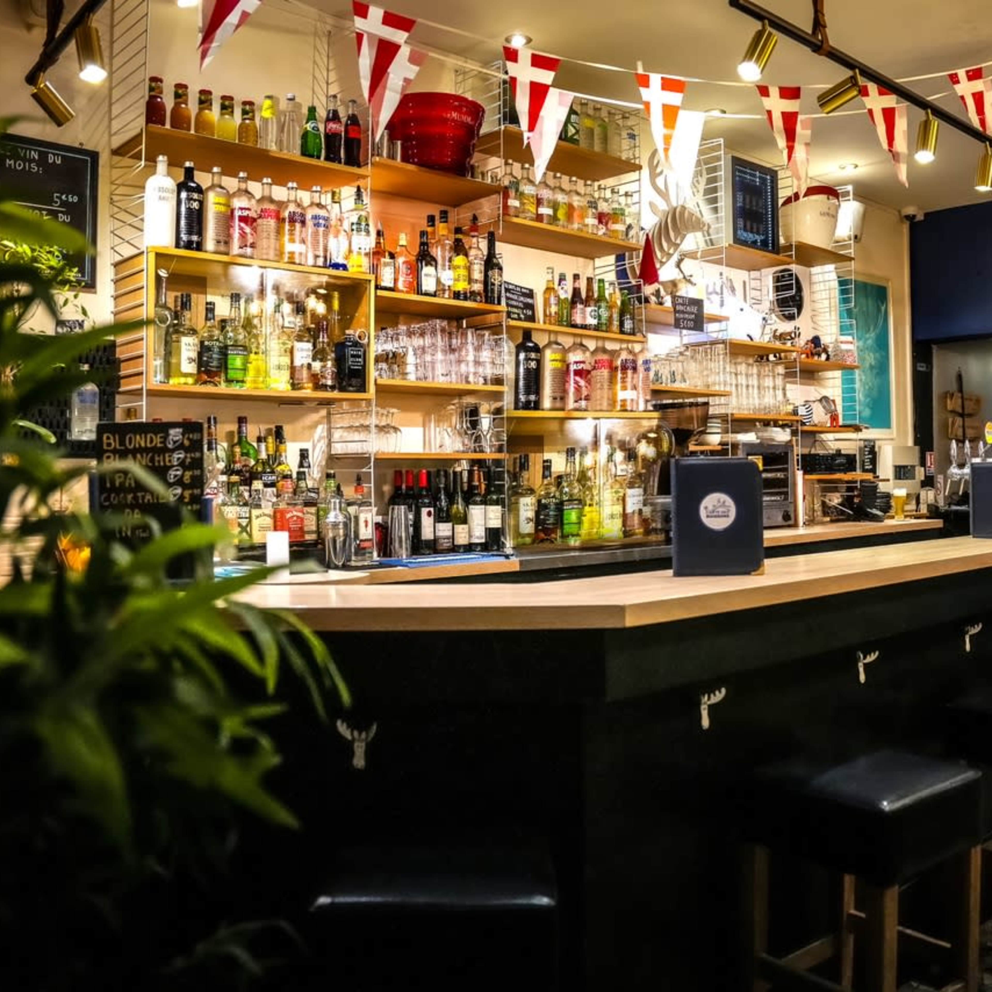 A well-stocked bar with a variety of bottles displayed on shelves and a neatly arranged counter with stools.
