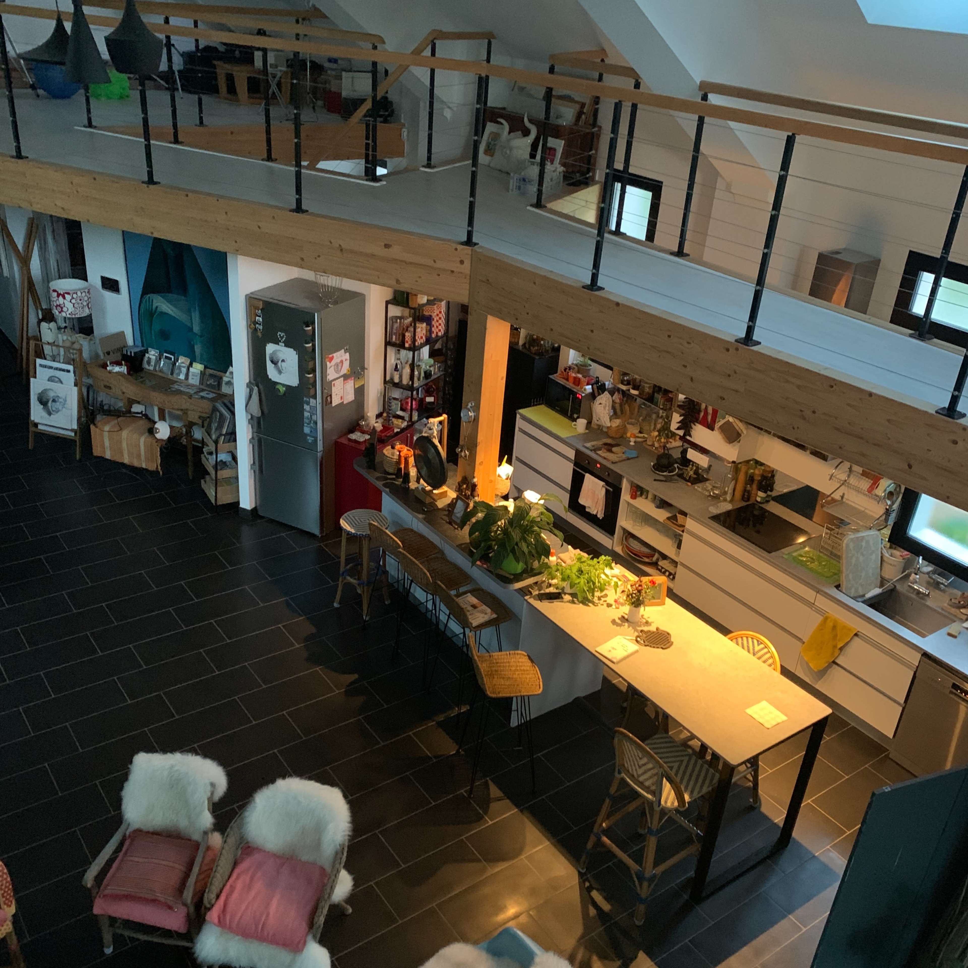 An open-concept living space with a kitchen and dining area on the lower level, and a lofted seating area above.