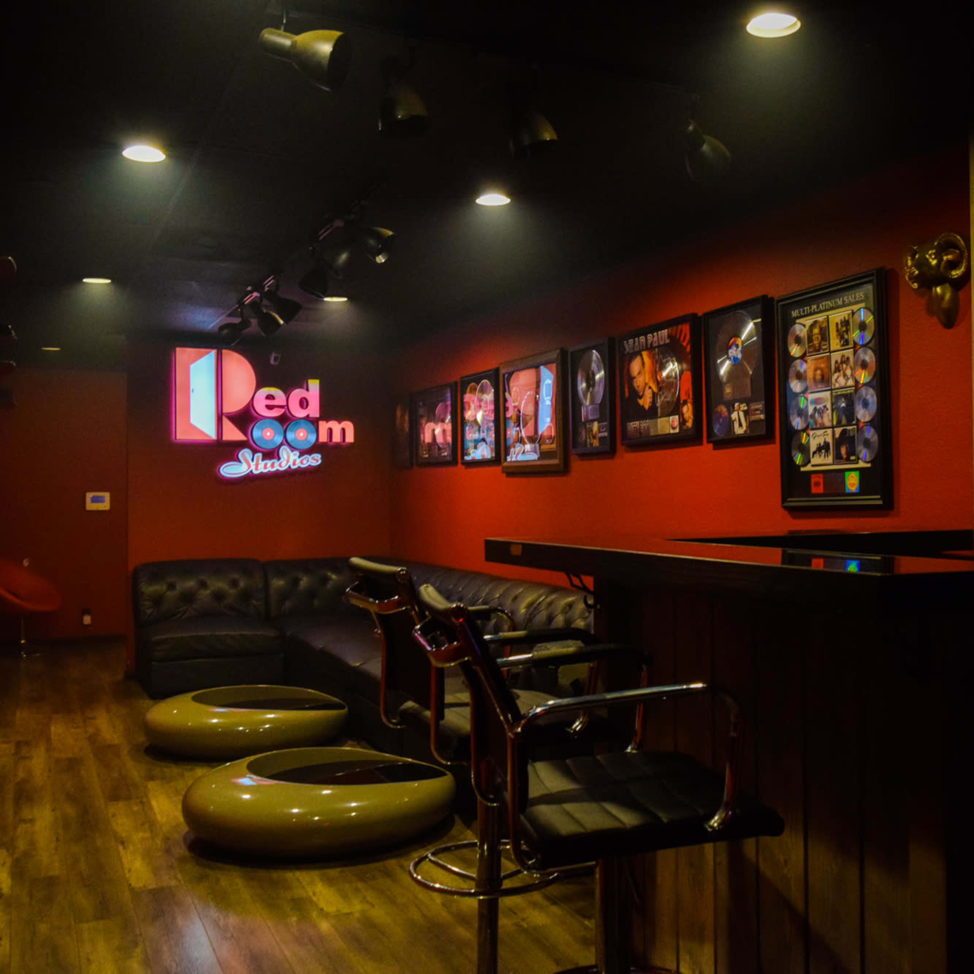 A dimly lit lounge with red walls, a bar setup, and several framed pictures on the walls.