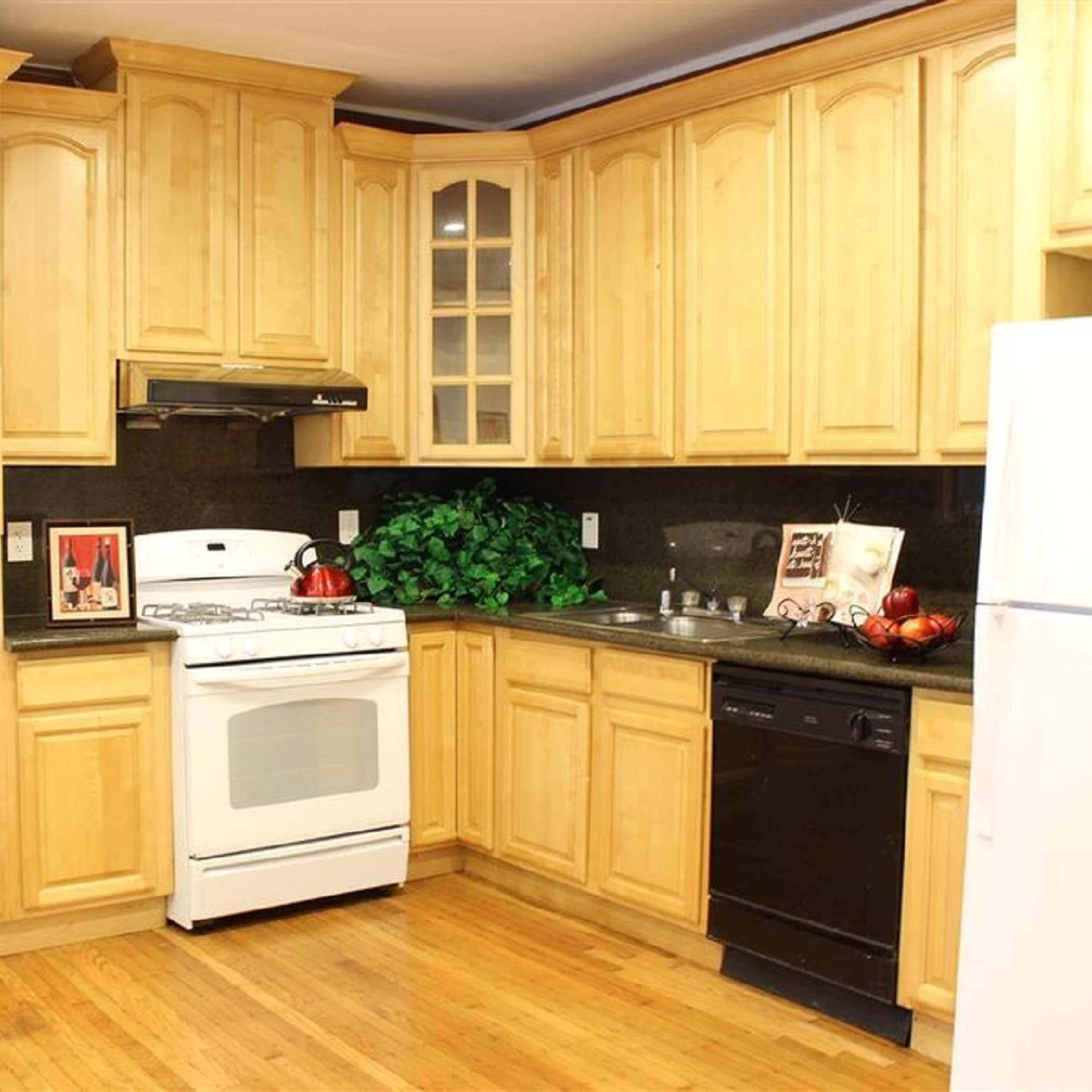 A kitchen with wooden cabinets, a white stove, a microwave, a dishwasher, and dark countertops.
