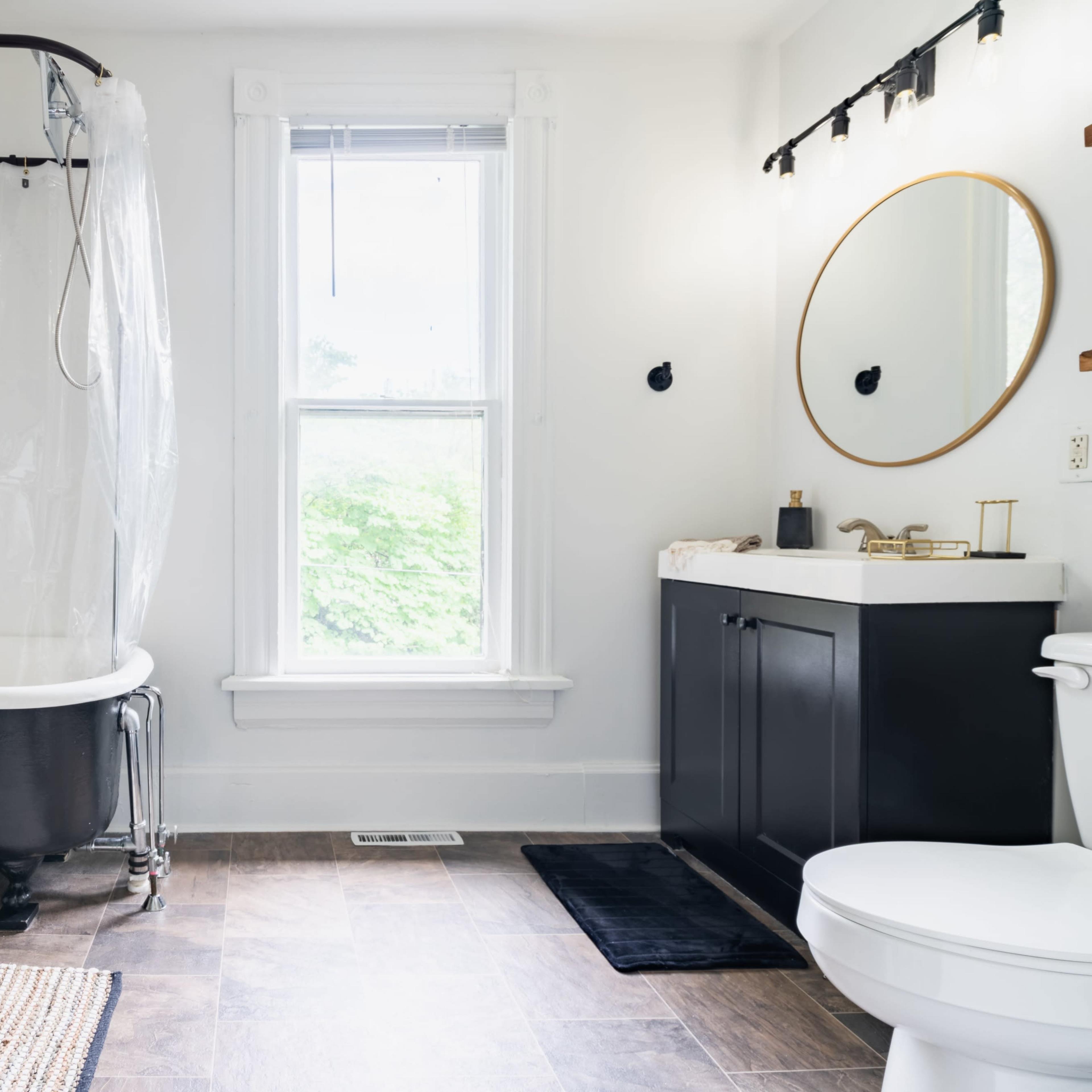 A bathroom features a freestanding bathtub, a modern sink vanity, and a large window with natural light illuminating the space.