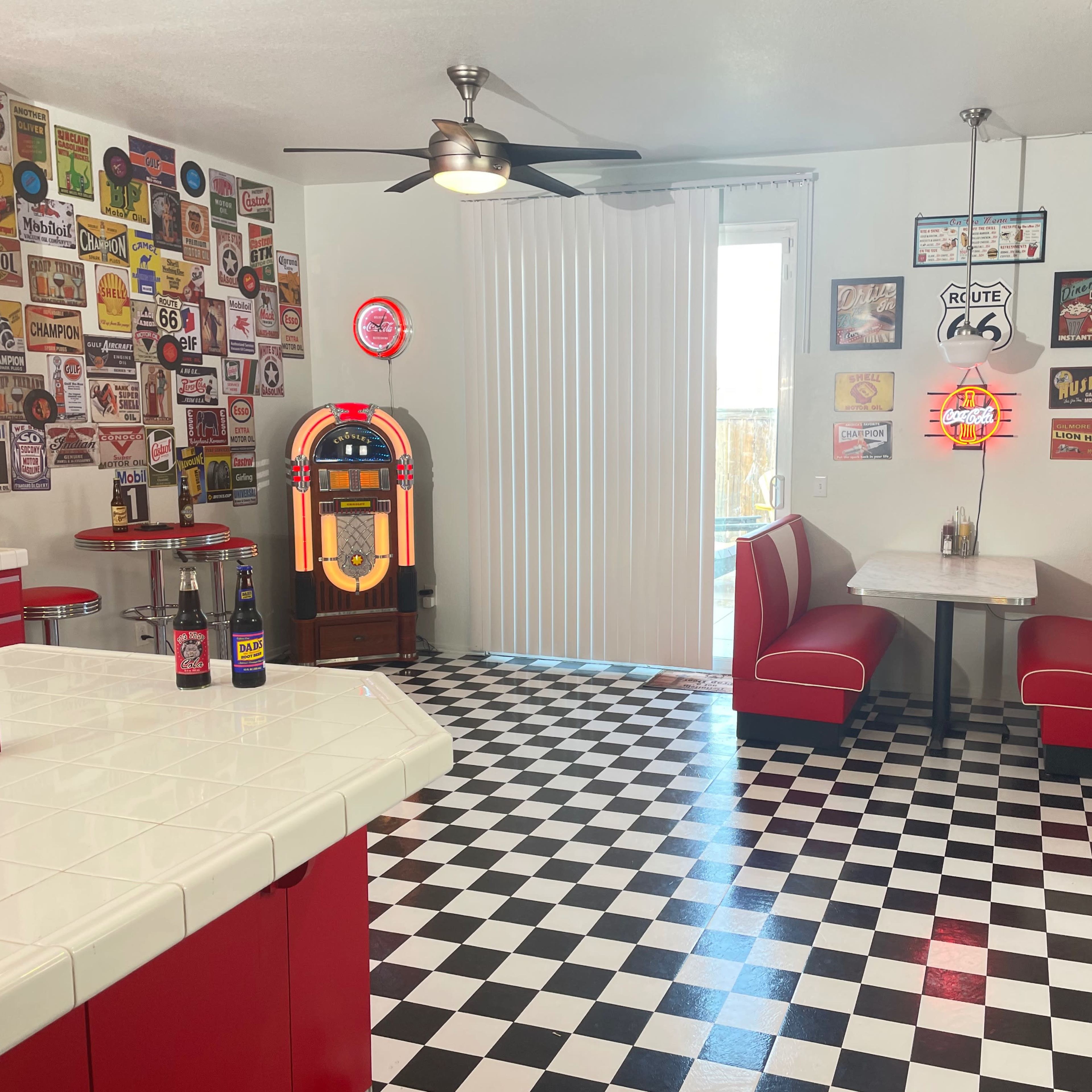 A retro-style diner interior with red and white decor, a jukebox, and a checkered black and white floor.