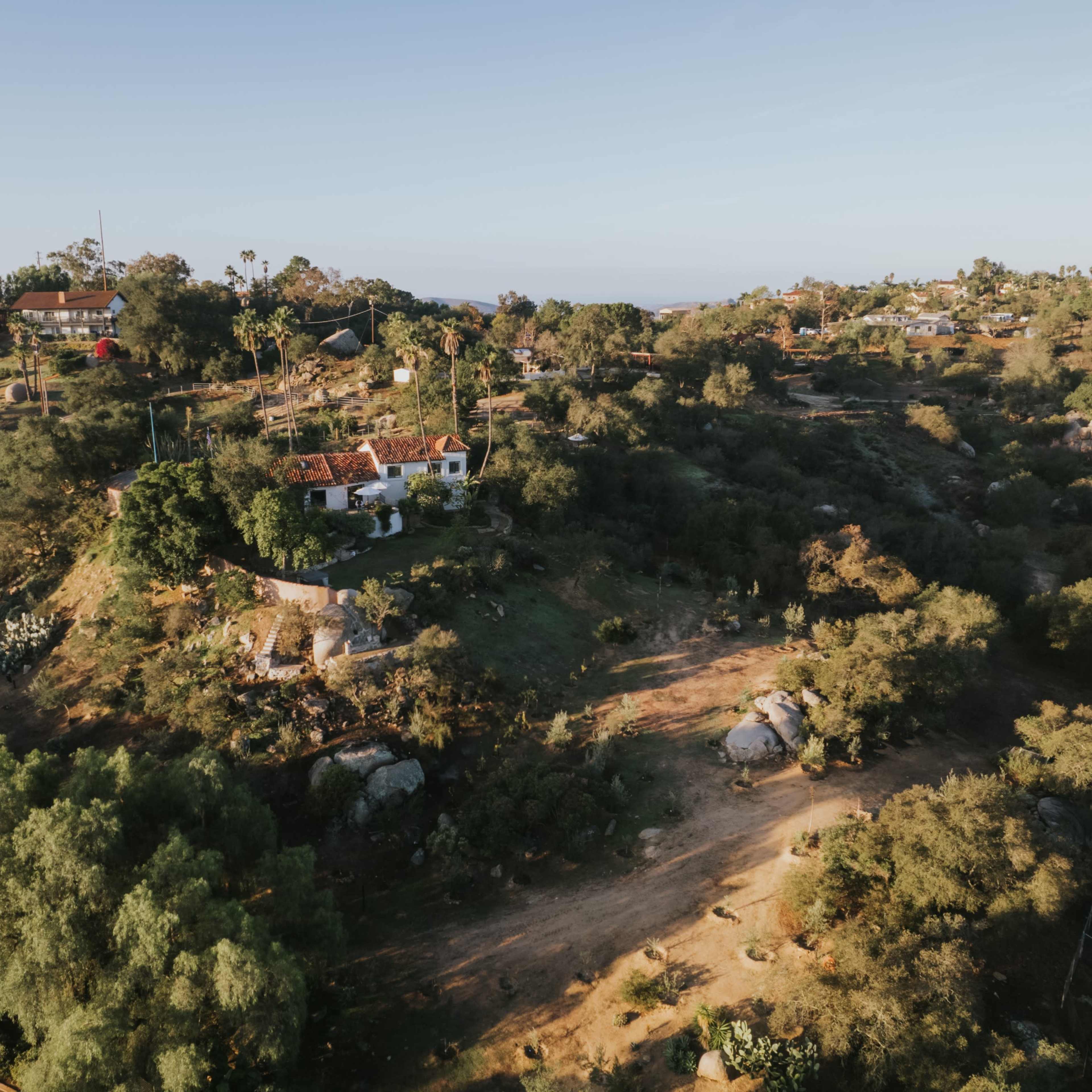 Aerial view of a hillside landscape featuring scattered homes and lush greenery.