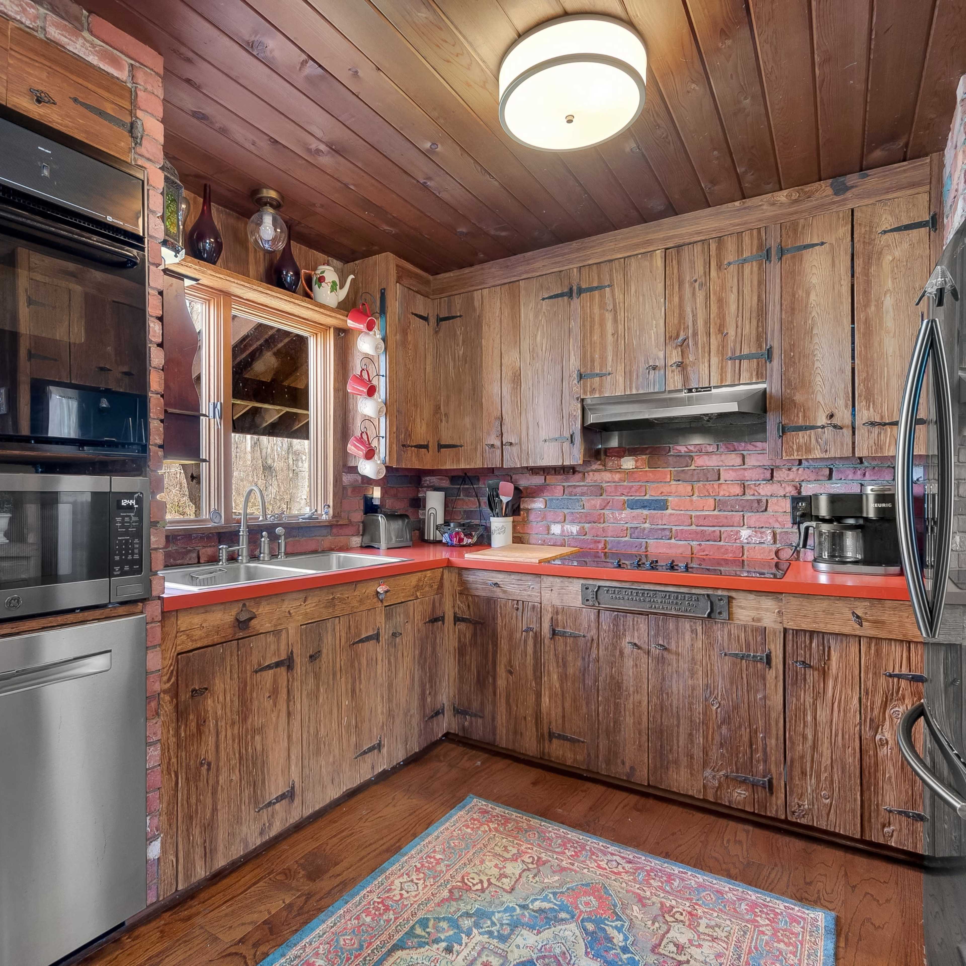 A rustic kitchen featuring wooden cabinets, a brick backsplash, modern appliances, and a central island.