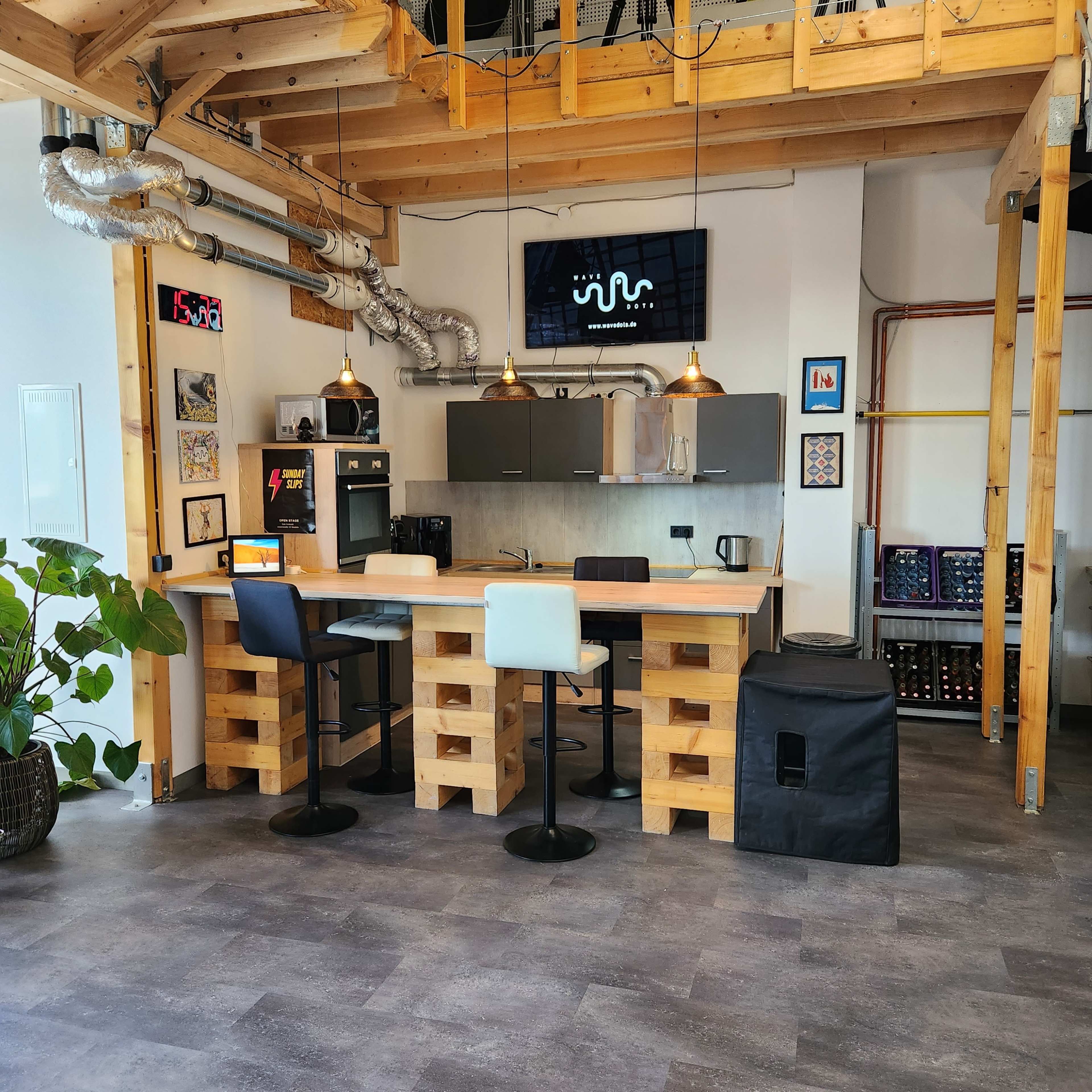 A modern kitchen area featuring a wooden bar with high stools, industrial-style decor, and various kitchen appliances.