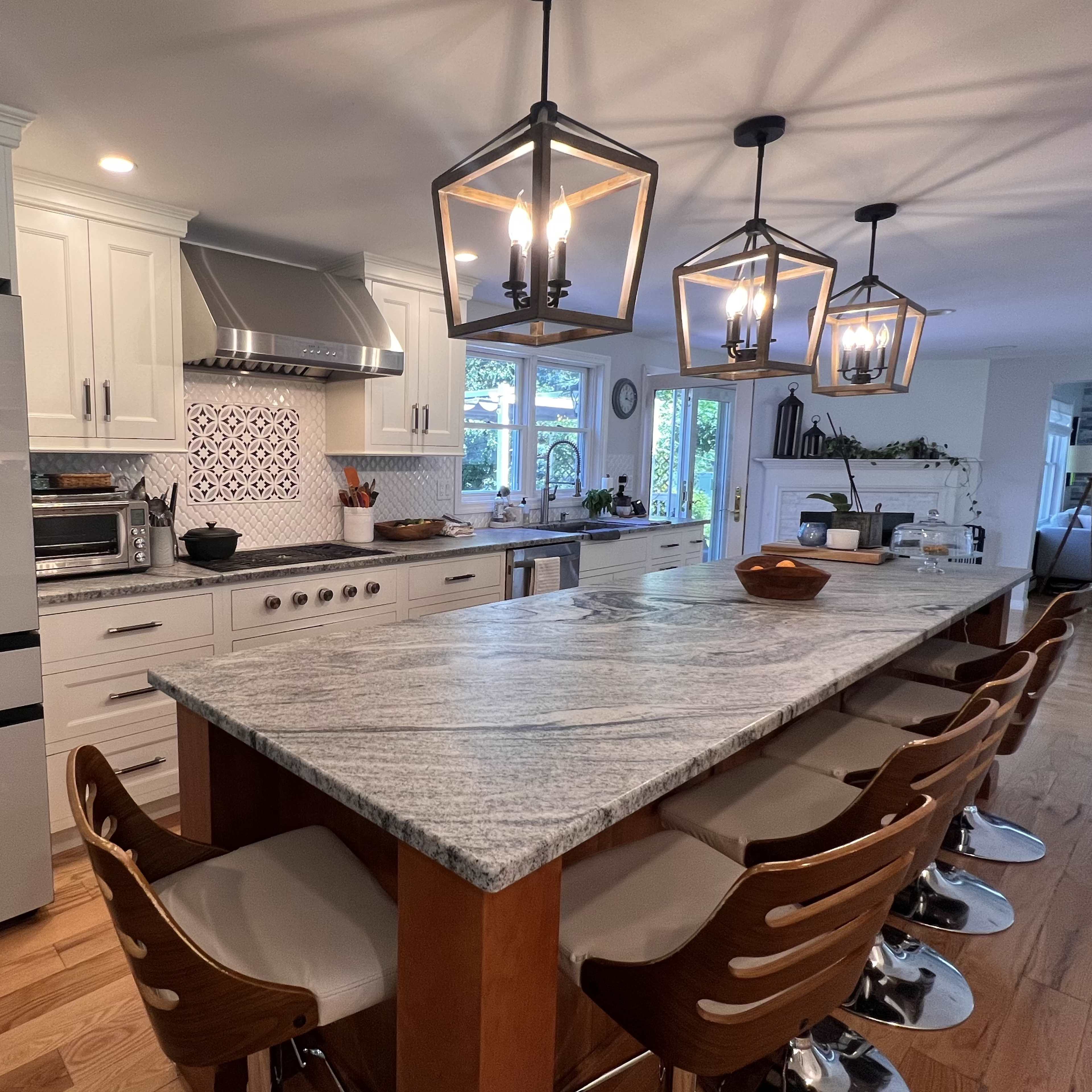 A modern kitchen with a large central island, pendant lighting, and white cabinetry.