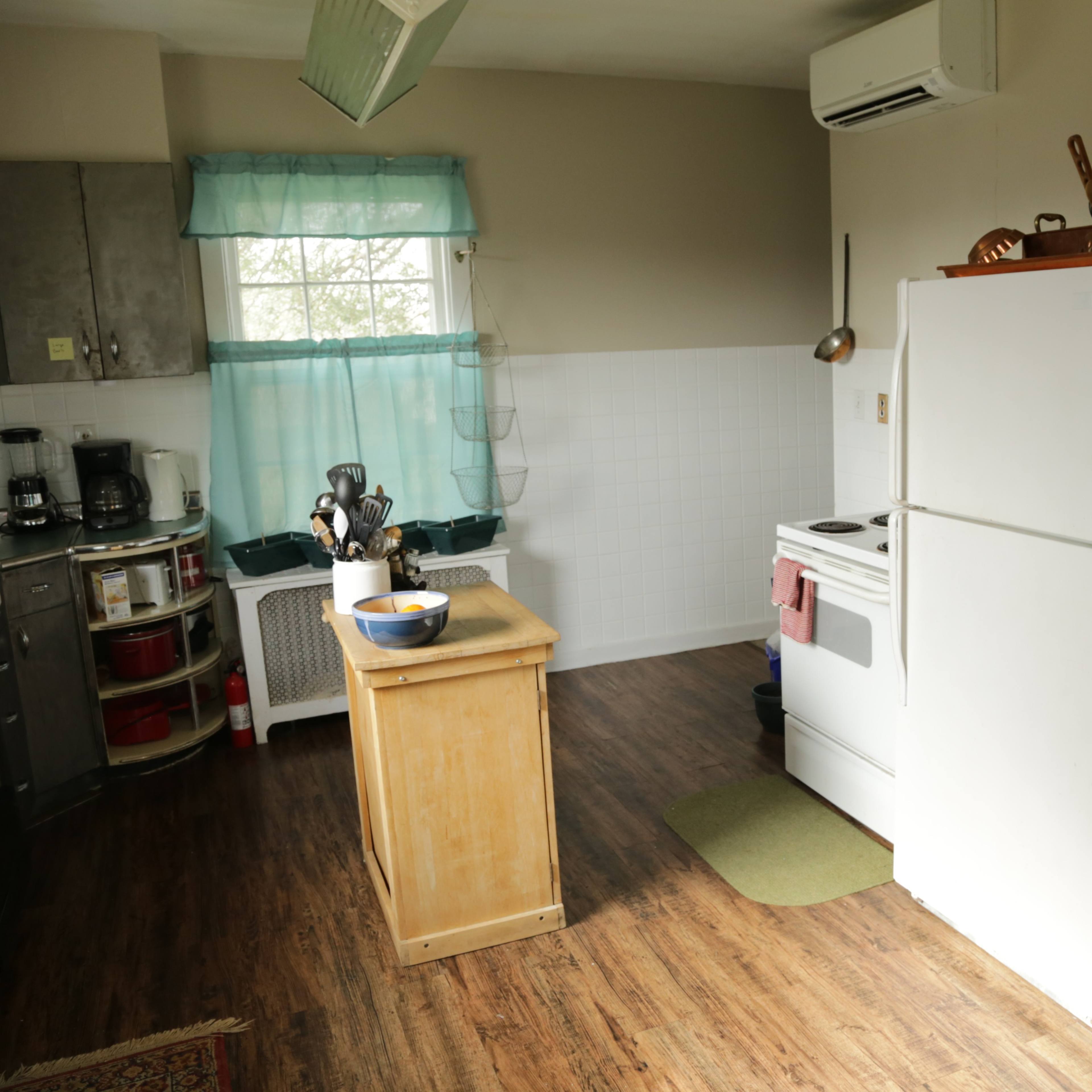 A kitchen with a white refrigerator, a wooden island, and various kitchen appliances arranged on metal countertops.